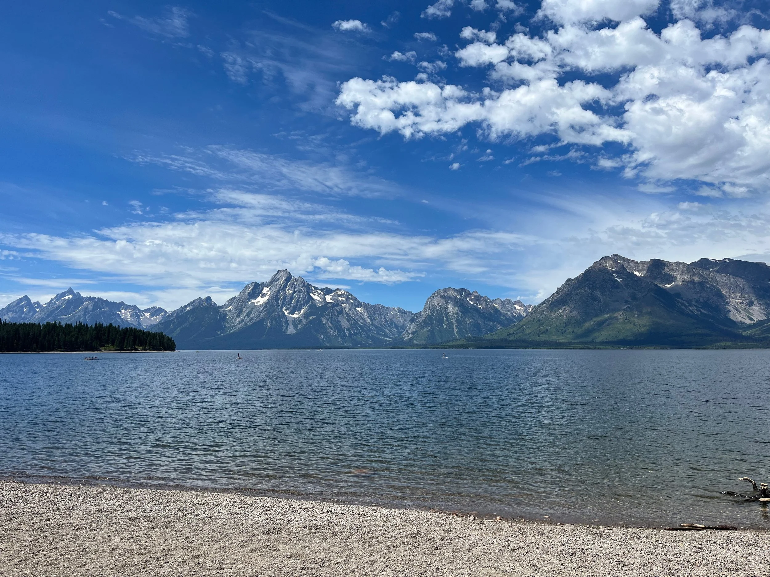 Scenic view of a lake with mountains in the background under a partly cloudy blue sky.