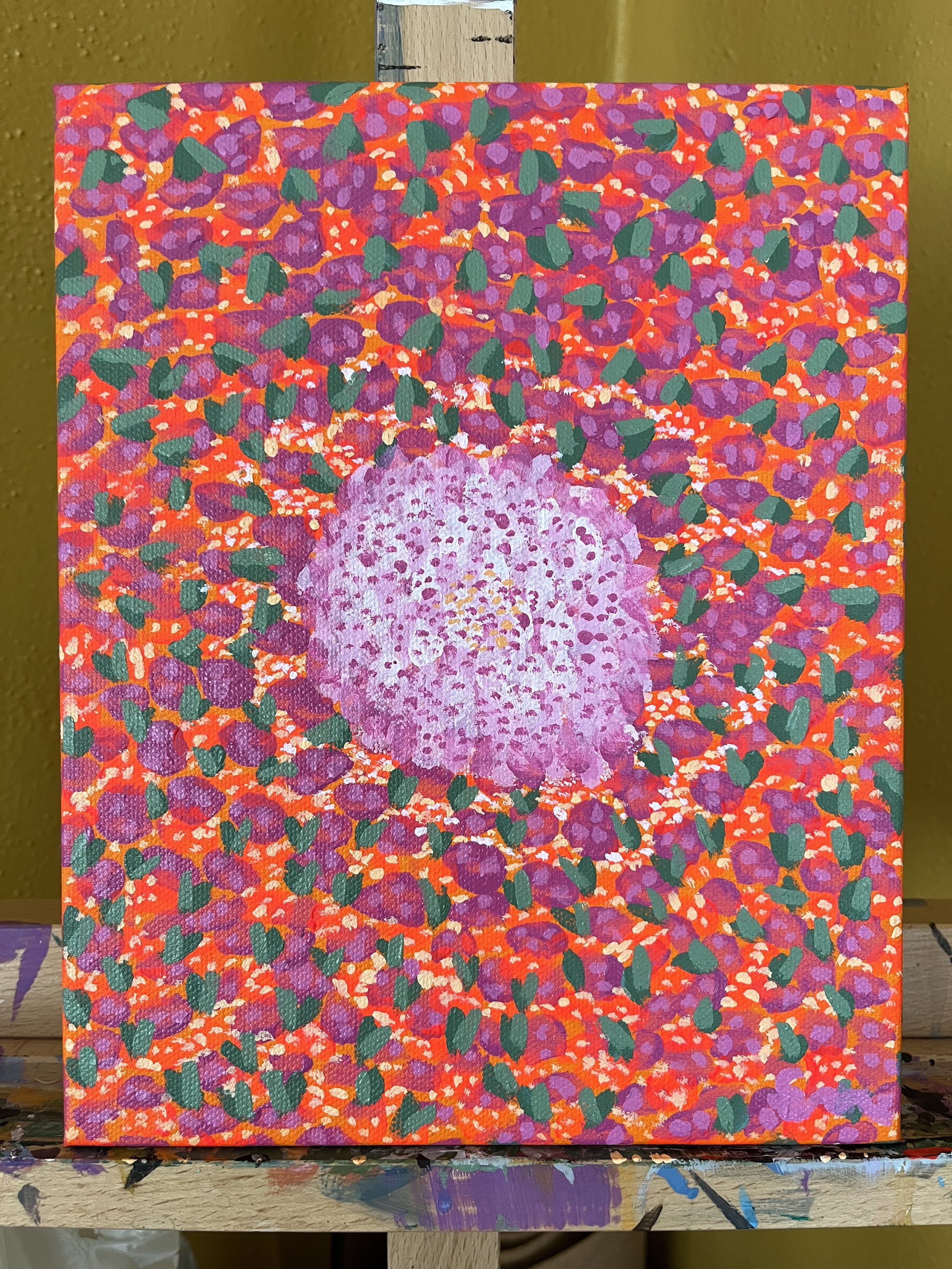 A colorful painting of a purple flower with a pink center surrounded by an abstract background of red, purple, green, and white dots and shapes.
