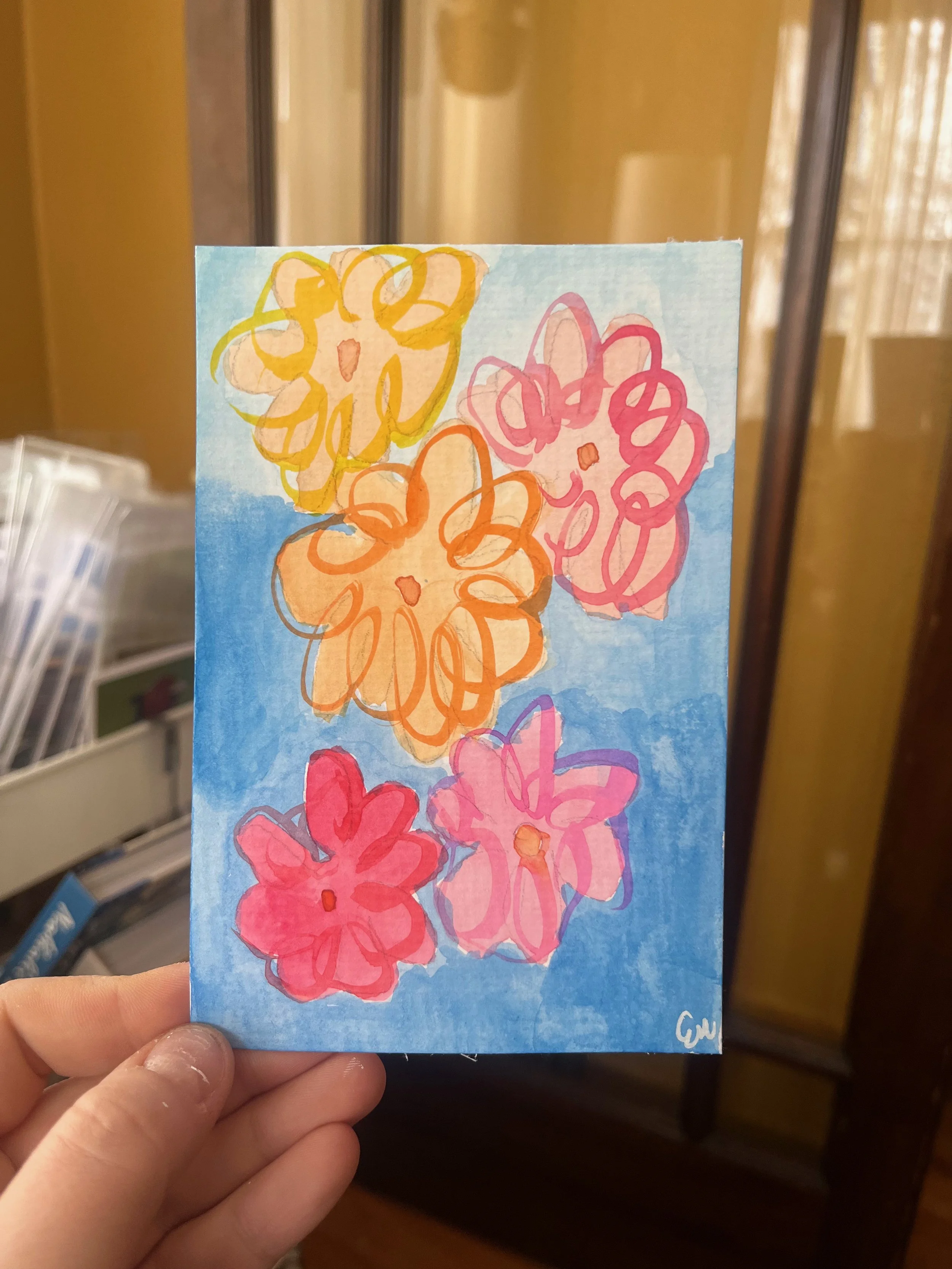 Handmade drawing of five colorful flowers on blue background, with yellow, pink, orange, and red blooms, signed with initials in the bottom right corner.