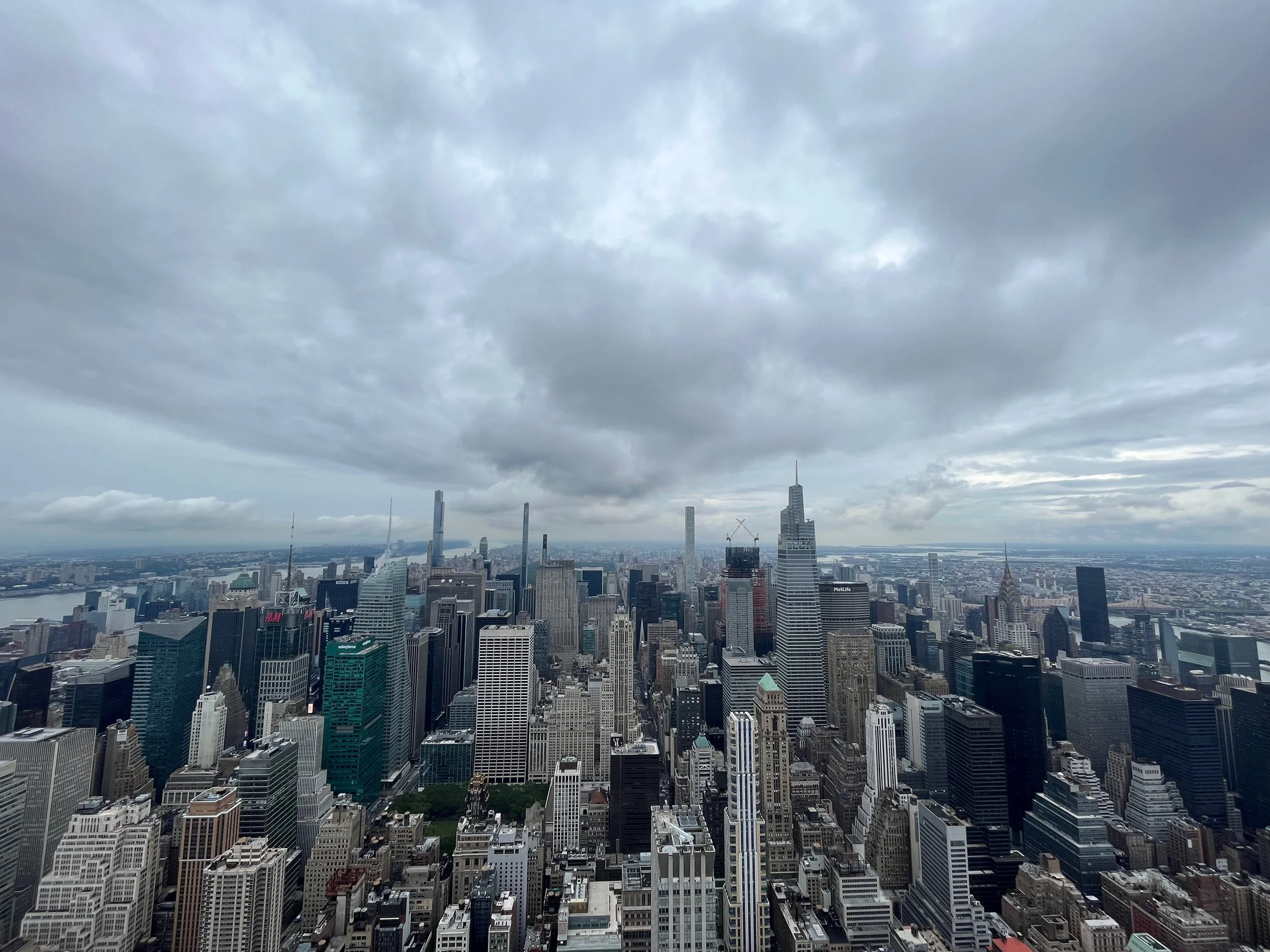 A panoramic view of a city skyline with numerous skyscrapers under a cloudy sky.