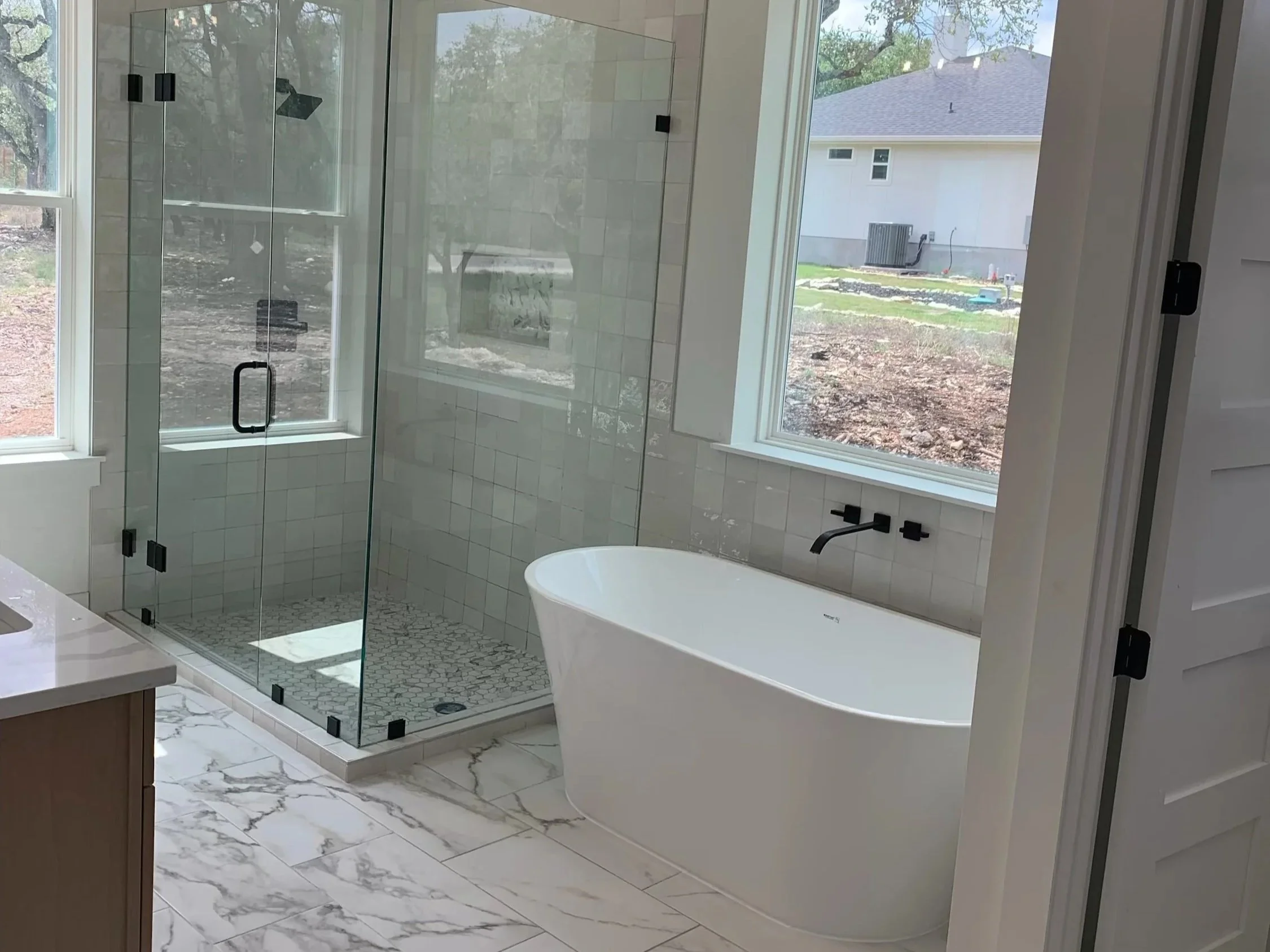 Modern primary bathroom with frameless shower glass and a giant soaking tub