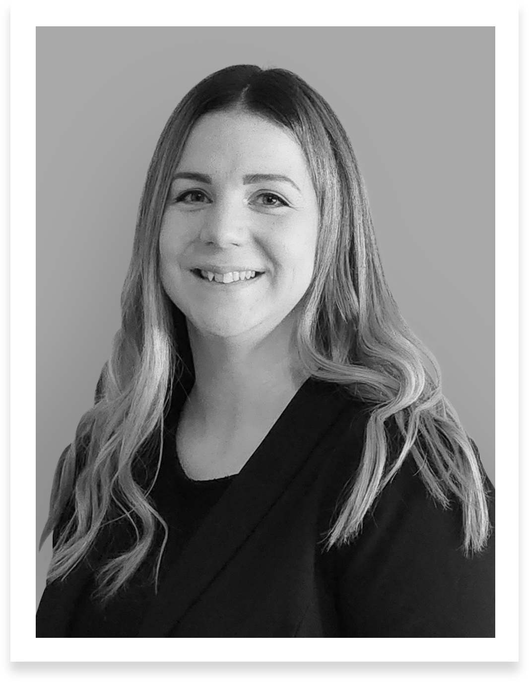 A black and white professional headshot of Adrienne Dozier, Director of Project Management at IIG Select. She is smiling warmly and wearing a dark blazer. Her long, wavy hair frames her face