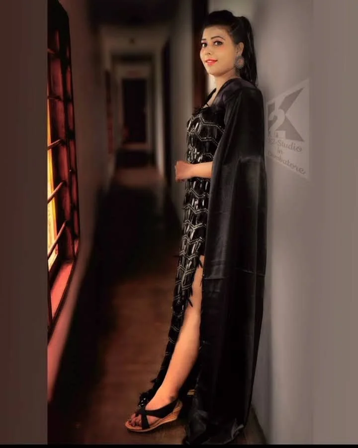 A woman wearing a black dress with a long cape in a hallway.