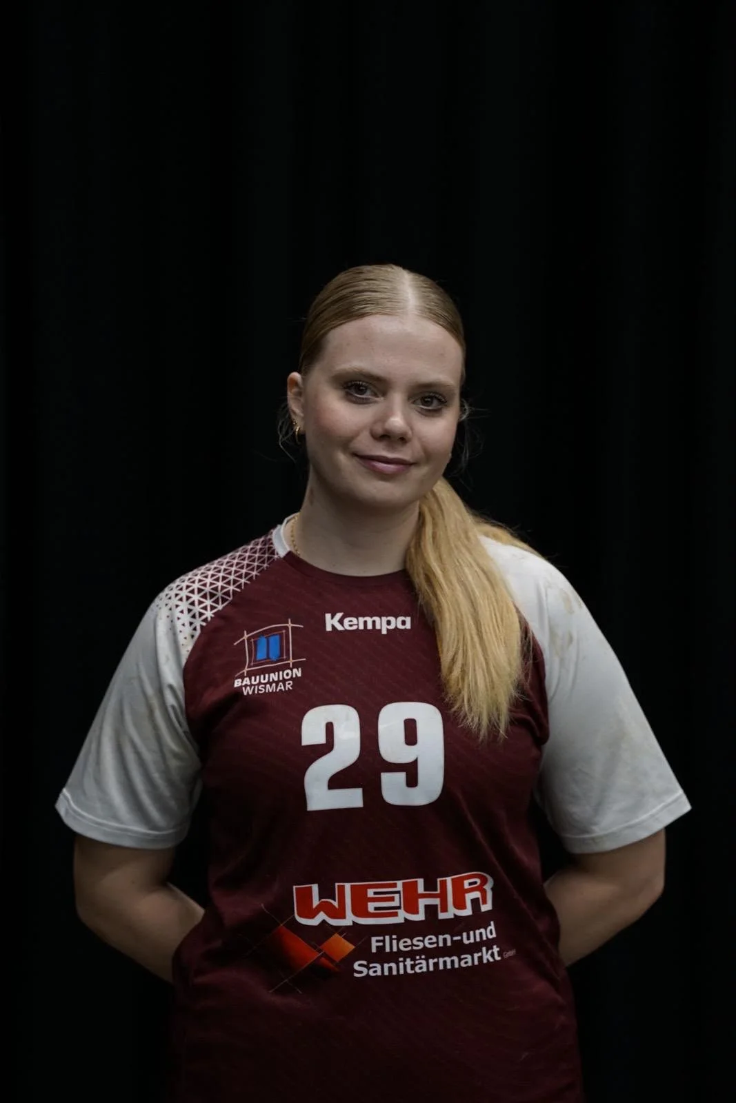 Frau in Handballtrikot mit Nummer 29 vor einem grünen Netz.