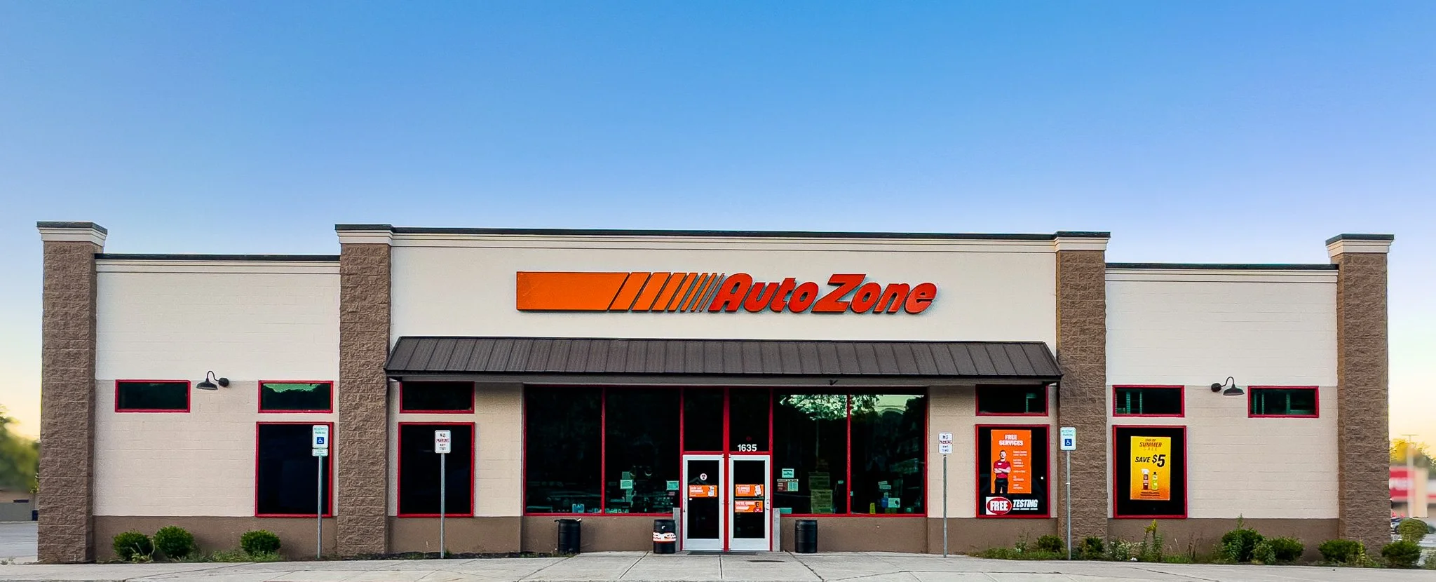 Exterior of an AutoZone store with a white facade, red signage, and large windows.