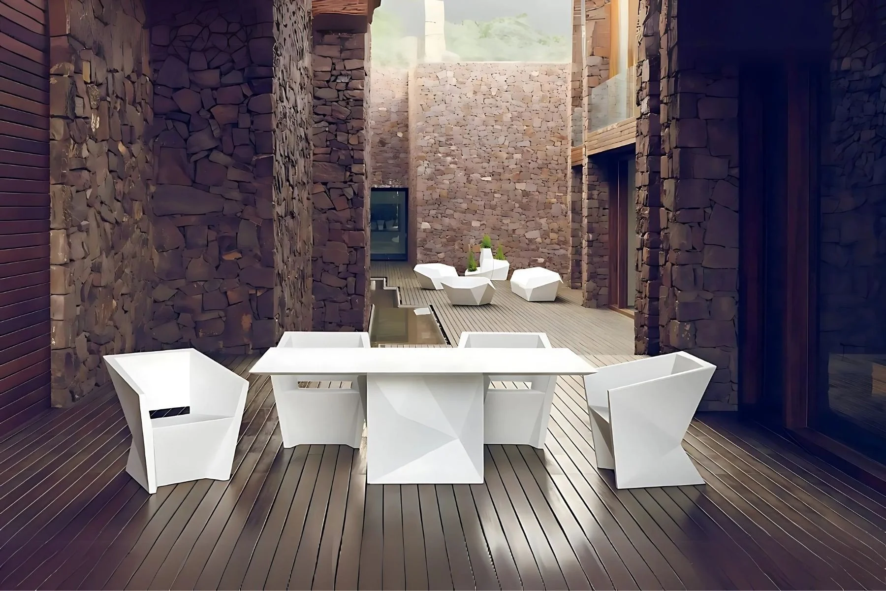 Mesa blanca con sillas modernas en balcón con paredes de piedra