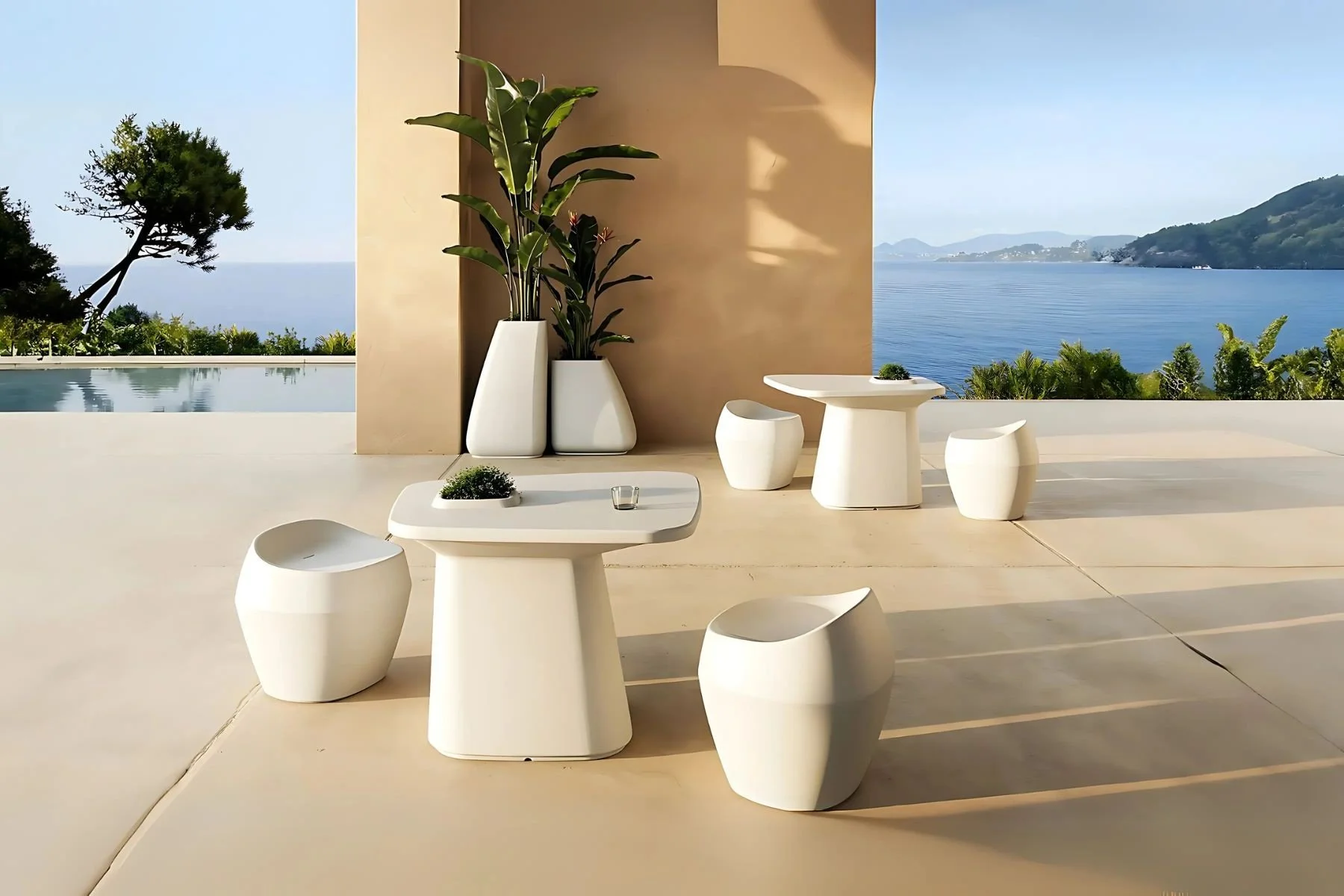 Terraza con mesas blancas y sillas minimalistas frente a vistas del mar y naturaleza