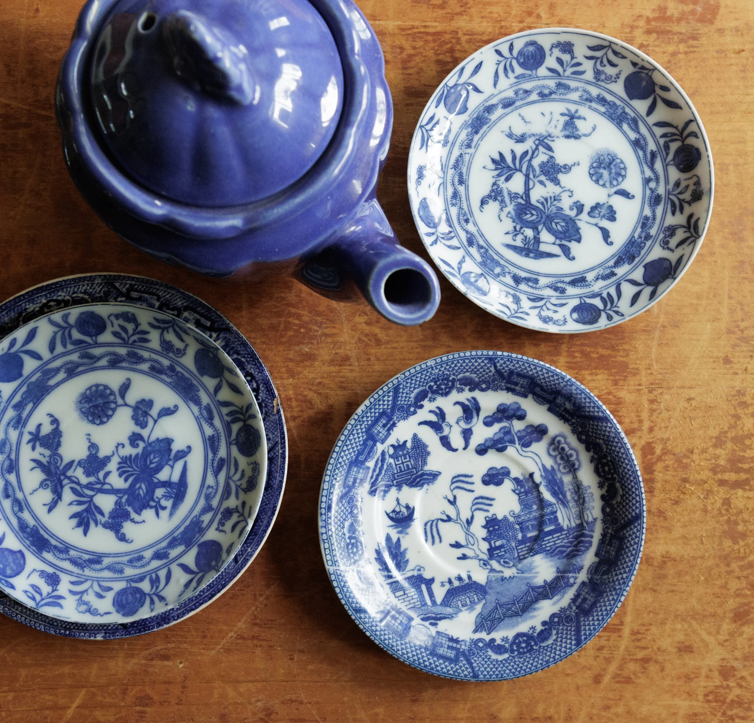 Blue and white porcelain plates with intricate floral and landscape patterns, arranged on a wooden surface.