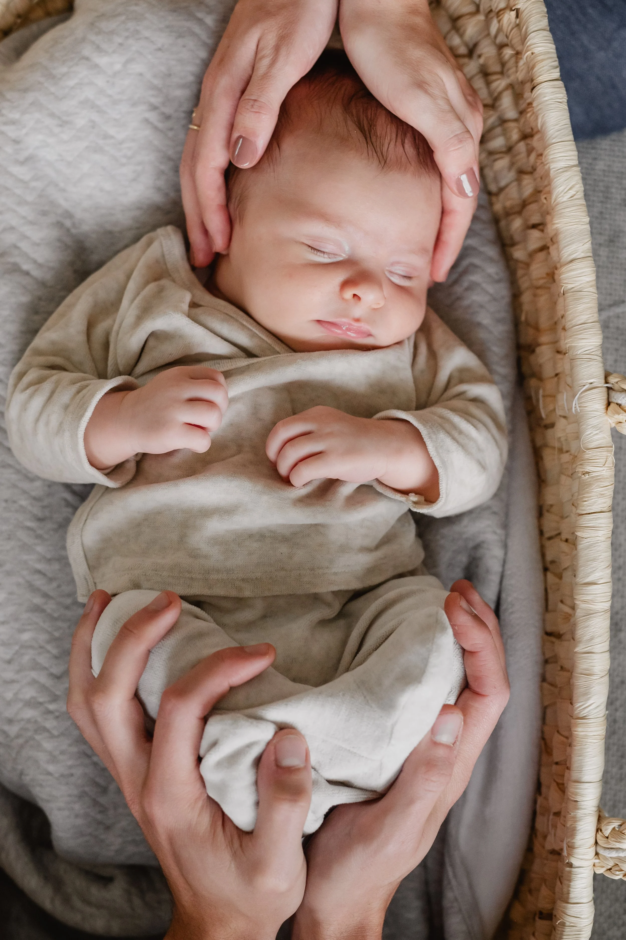 Een slapende baby in een wieg, omringd door volwassenen die hem zacht vasthouden.