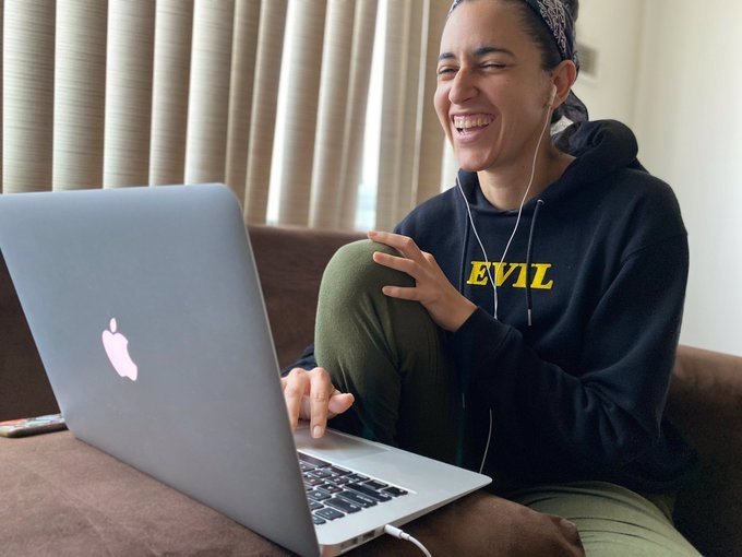 Woman smiling and laughing while presenting a workshop using a laptop.