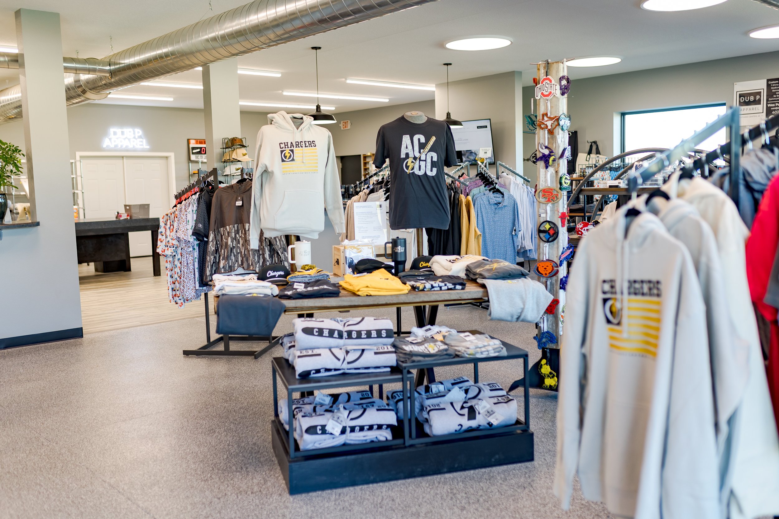 Display of sports apparel and merchandise in a retail store, including hoodies, T-shirts, and caps with Chargers team logos and colors.
