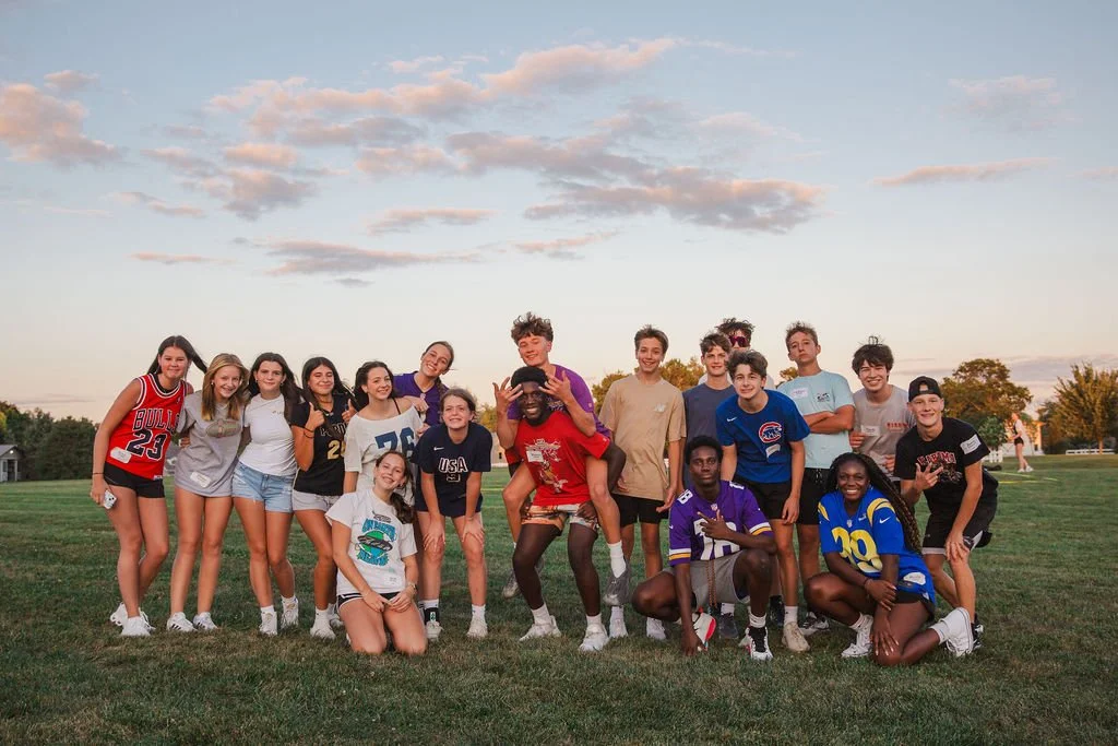 group of friends standing together hugging with a morning sky behind them