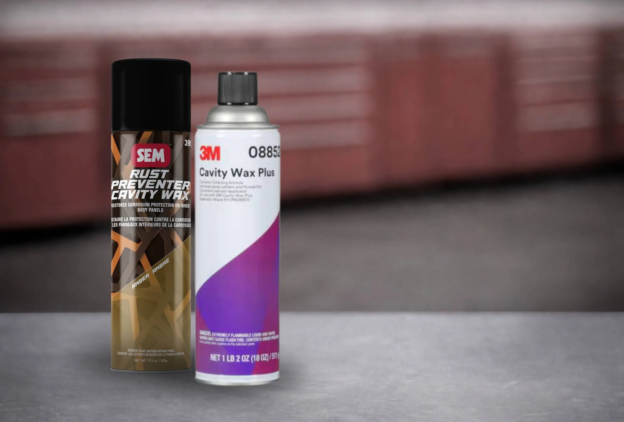 Two cans of cavity wax sit on a counter top in an industrial or automotive setting.