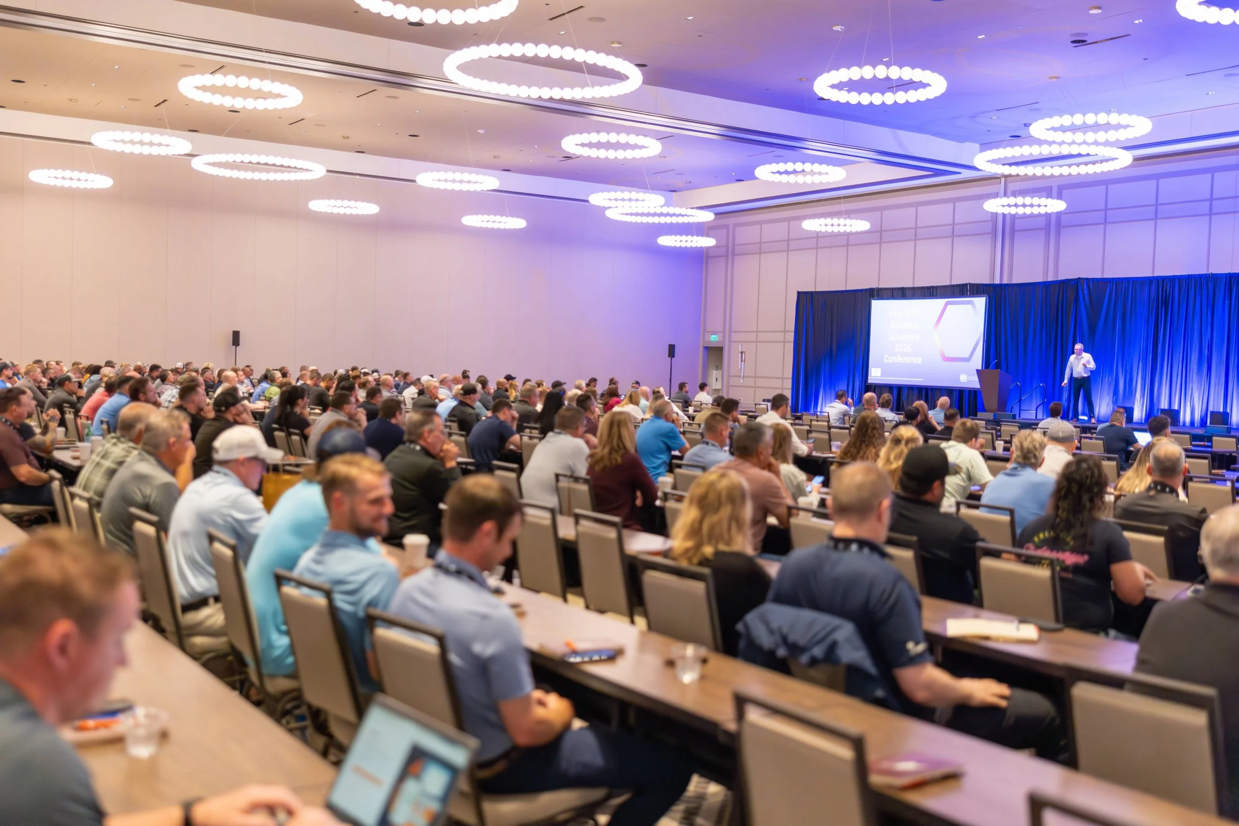 A conference room is filled by attendees listening to a keynote speaker at the 2026 PPG MVP Business Solutions Conference.