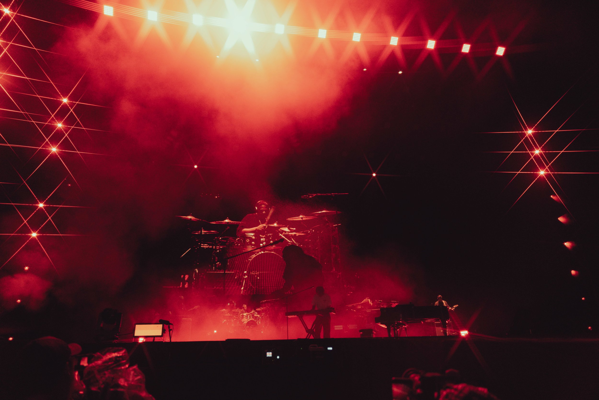 Musicians performing on stage with red lighting and star-shaped light effects.