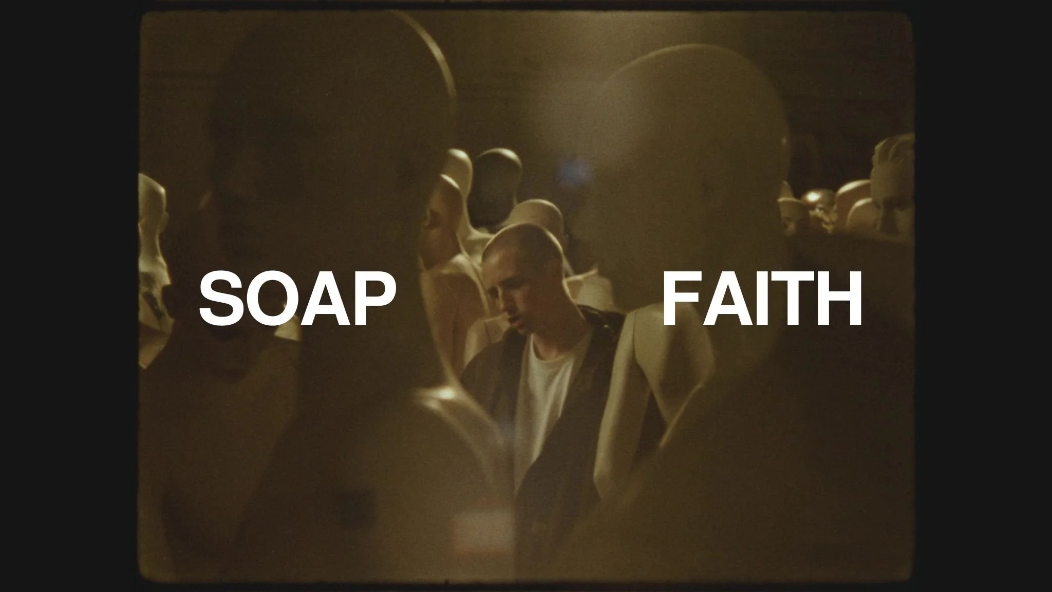 A group of people, mostly young men, standing close together in a dimly lit space. Overlaid on the image are the words 'SOAP' on the left and 'FAITH' on the right in large, white text.