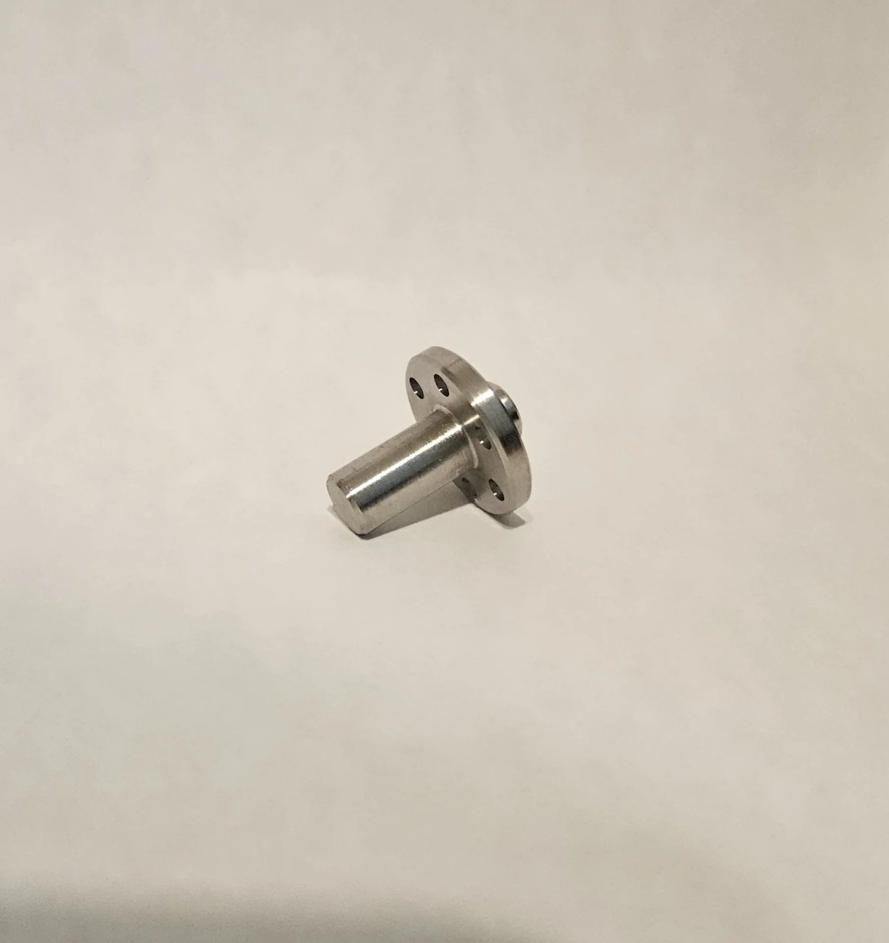 Precision Swiss machined stainless steel flange component with cross-drilled holes and tight-tolerance geometry.