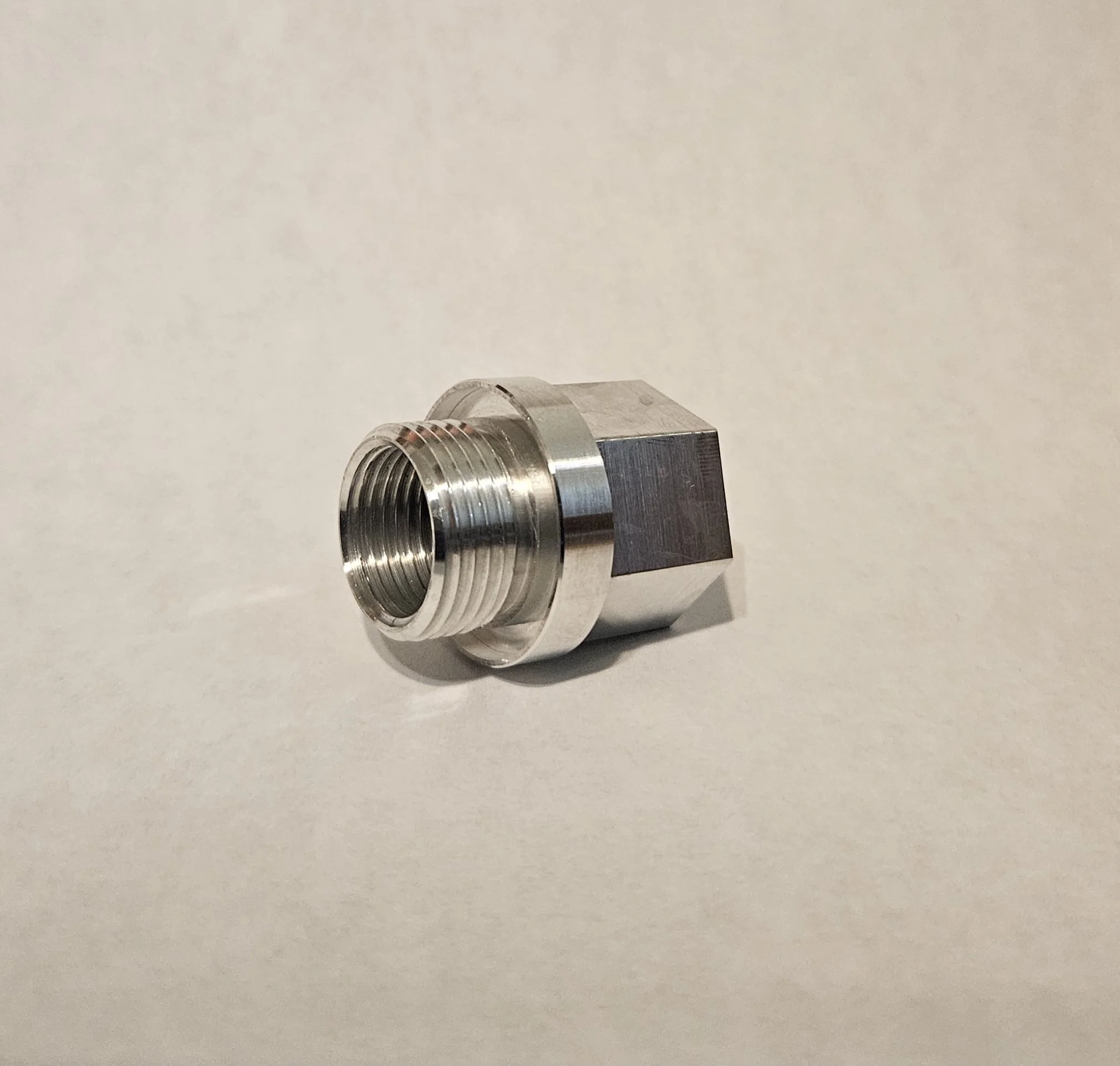 Precision aluminum threaded adapter completed in a single operation on a Swiss-type CNC lathe. Features external threading, bored diameters, and machined wrench flats