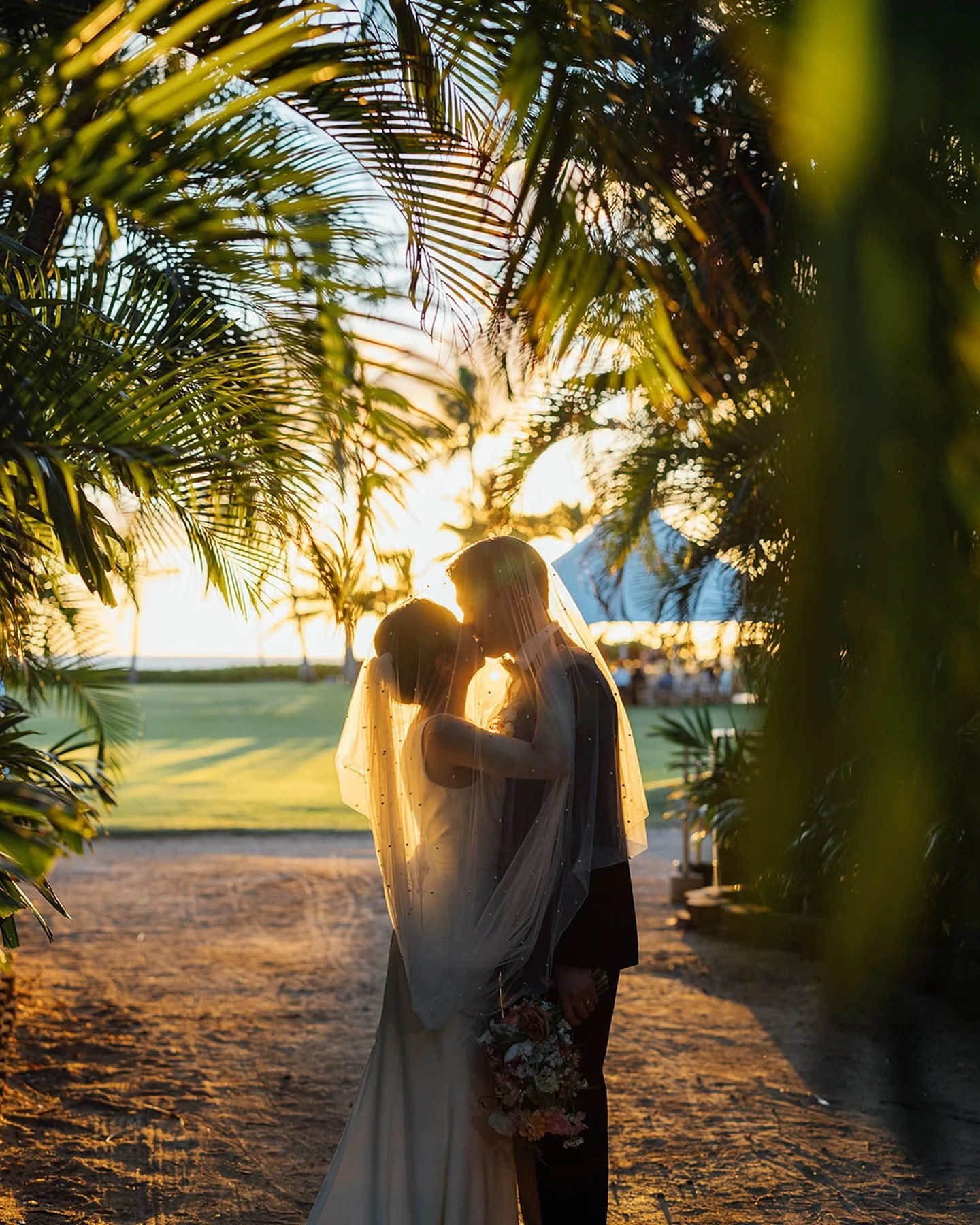 Capturing the fleeting perfect moment of a wedding day&mdash;a kiss to seal forever, framed by a veil of pearls, under the golden hour glow.