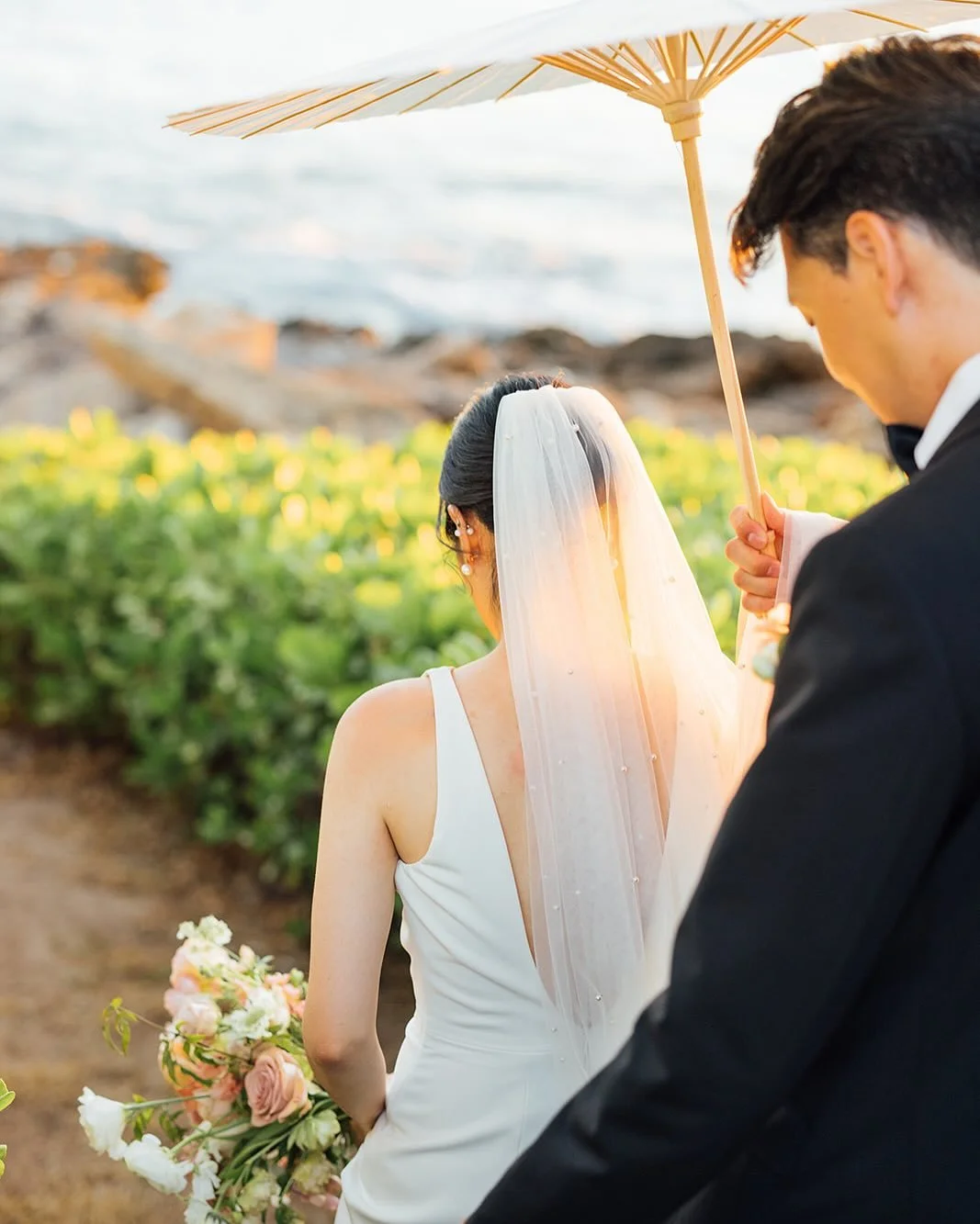 Golden hour magic with our newlyweds: a soft sunset, ocean breeze, and a romantic parasol to complete the moment. The groom&rsquo;s gentle escort is a reminder that love truly shines brightest by the sea. 🌅