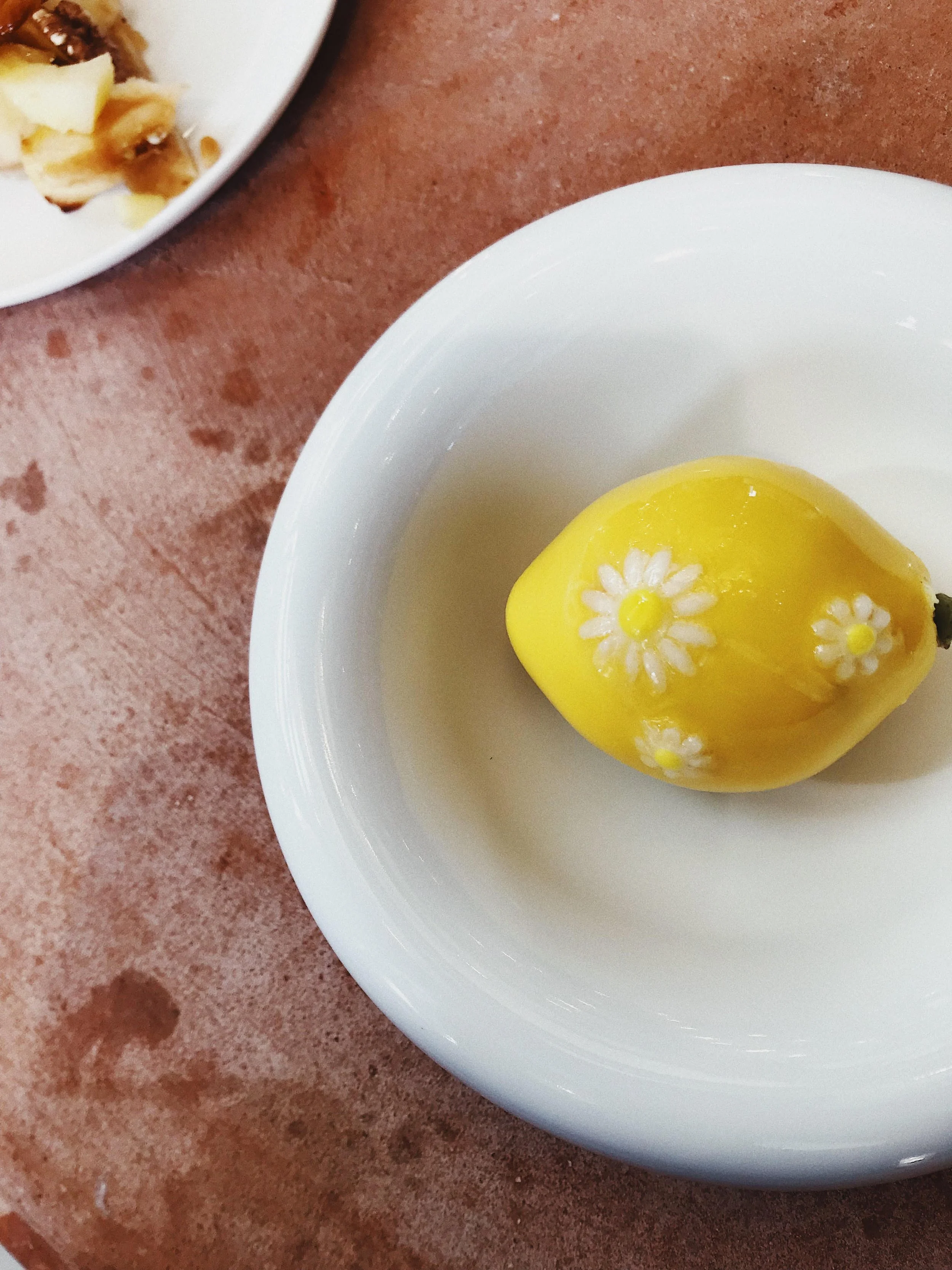 Yellow candle with white flower decorations on a white plate