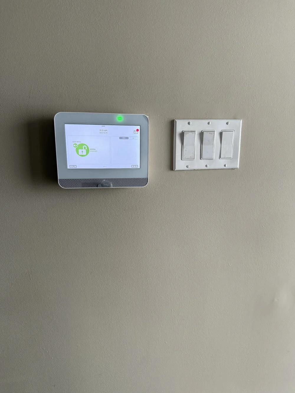 Wall mounted touchscreen alarm panel showing the system ready