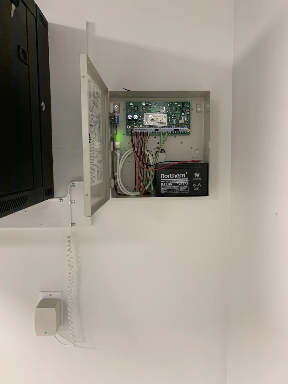 DSC alarm panel enclosure open on a basement wall with battery backup