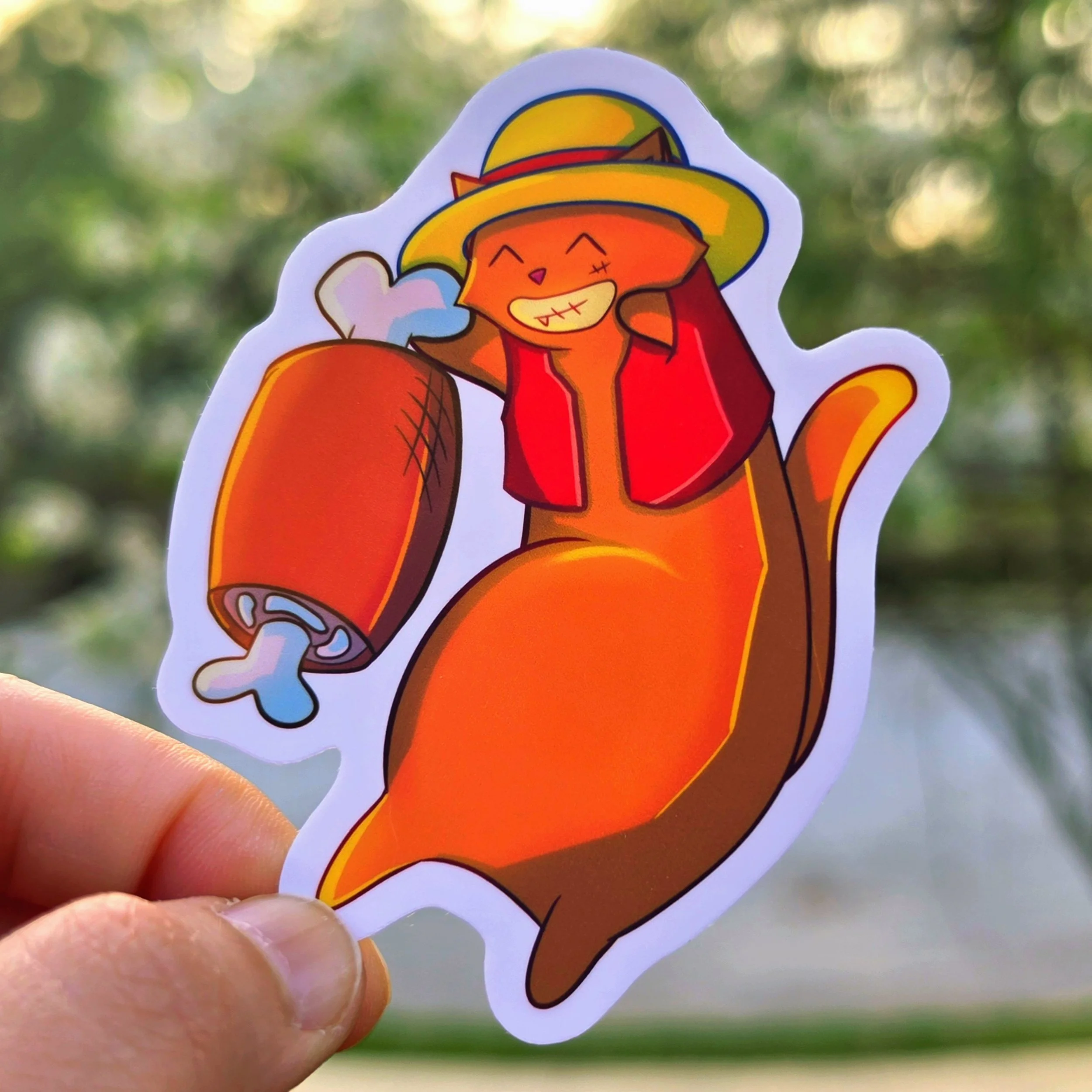 The Captain (Luffy): A die-cut vinyl sticker of a black and white cat reimagined as Monkey D. Luffy. The cat wears a signature yellow straw hat with a red band and features a wide, toothy grin while holding a meat
