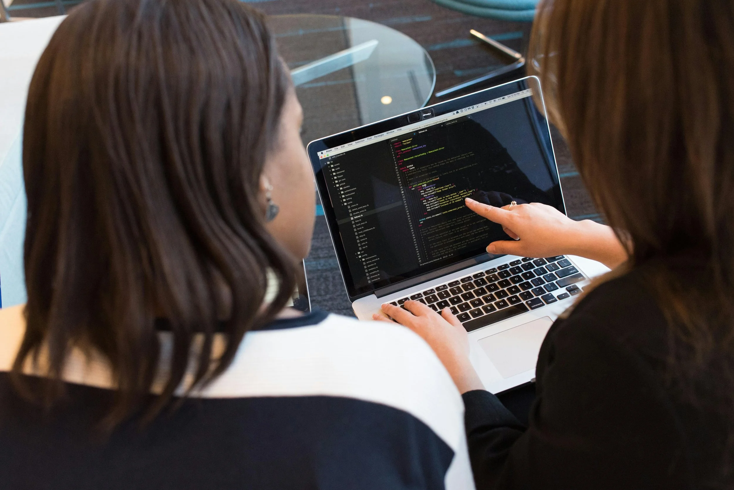 Two women reconfiguring a program running on a laptop.
