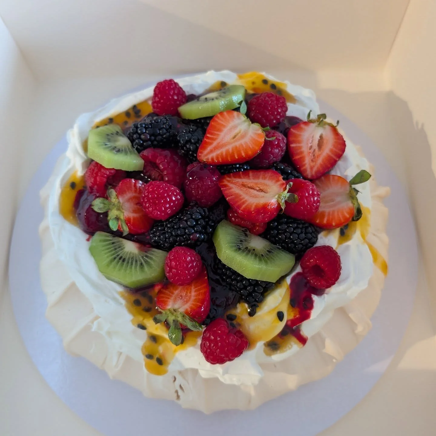Pavlova. Nom, nom. 😋  Mixed berry compote, passion fruit reduction, fresh berries, fresh kiwi fruit and Flora plant based thickened cream.