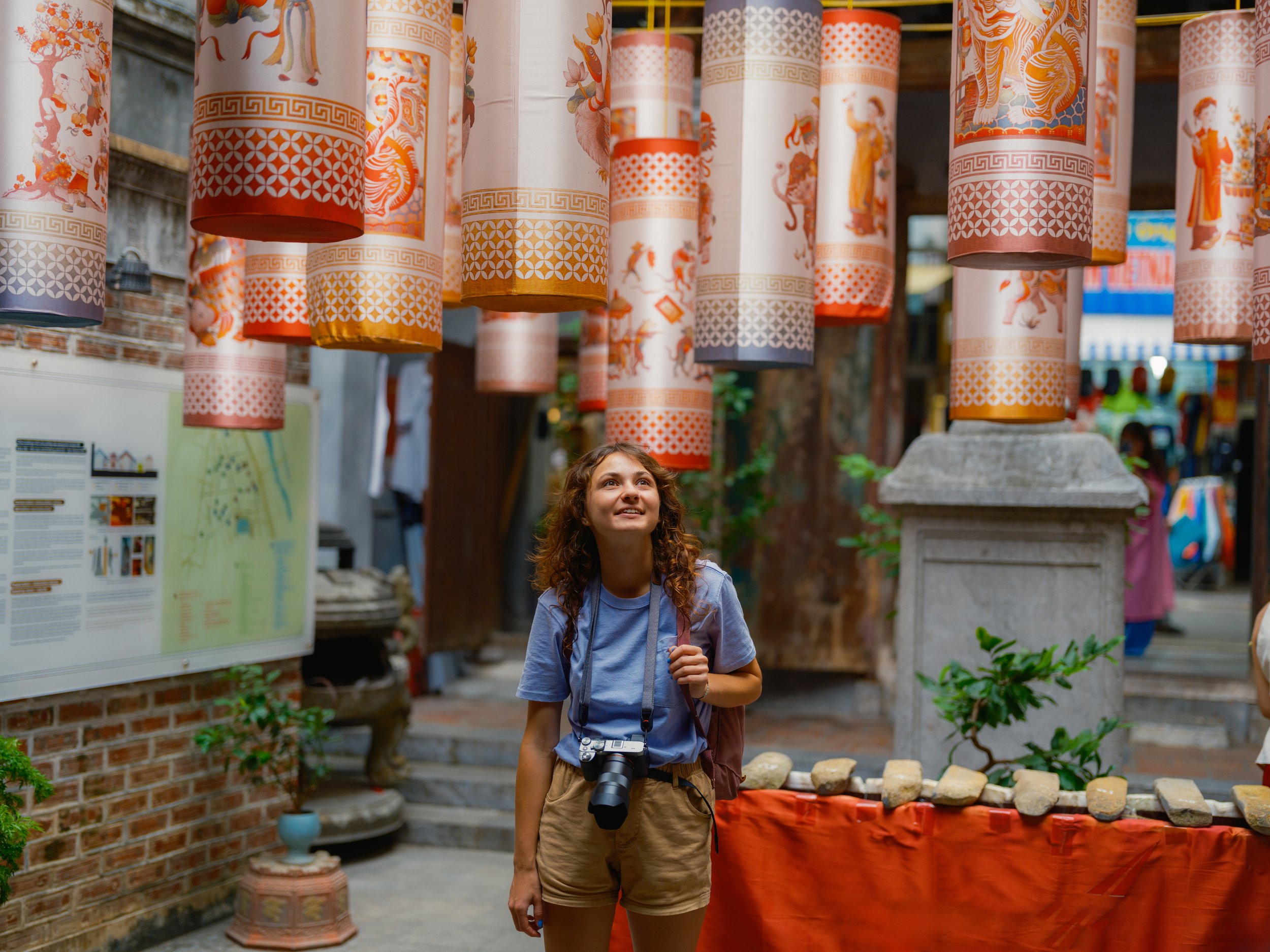 University student exploring a cultural site decorated with traditional lanterns during overseas experience in Asia.