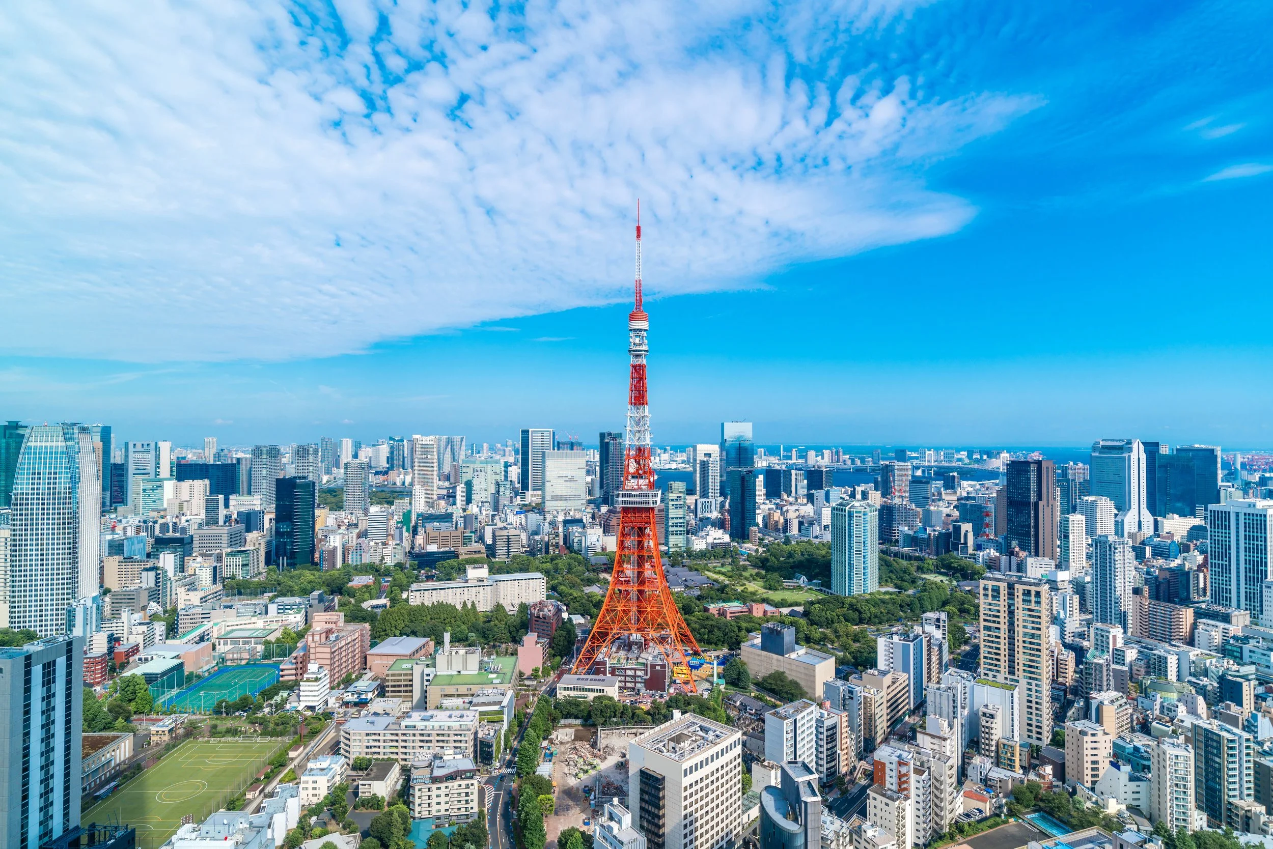 Aerial view of Tokyo city skyline featuring Tokyo Tower surrounded by modern buildings.