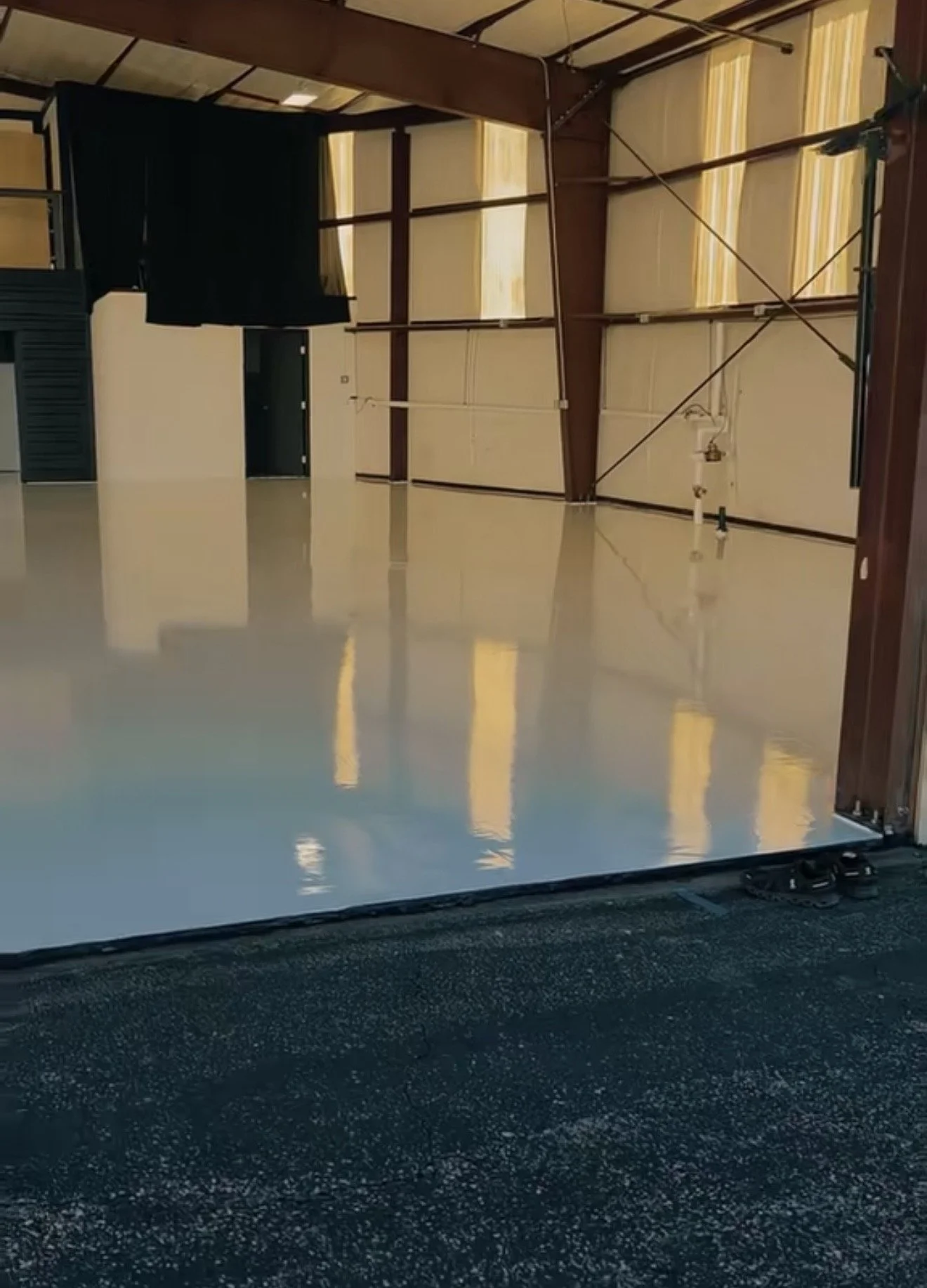 A garage door partially open, revealing a shiny white floor inside the garage.