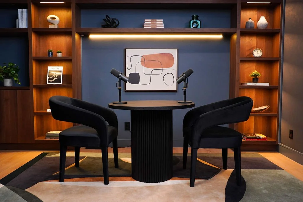 Brooklyn set at Venice Podcast Studio featuring a round black table and chairs against a navy blue wall with built-in bookshelf
