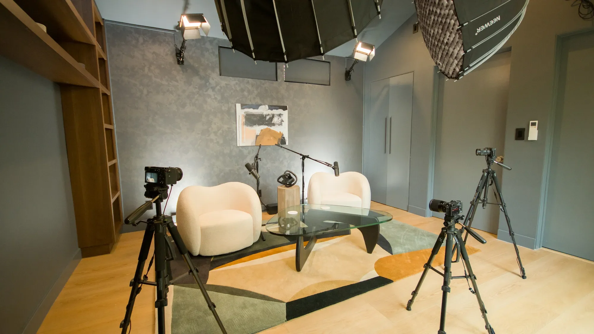 Professional video cameras on tripods inside the Dark Studio at Venice Podcast Studio in Los Angeles, with podcast interview seating in the background