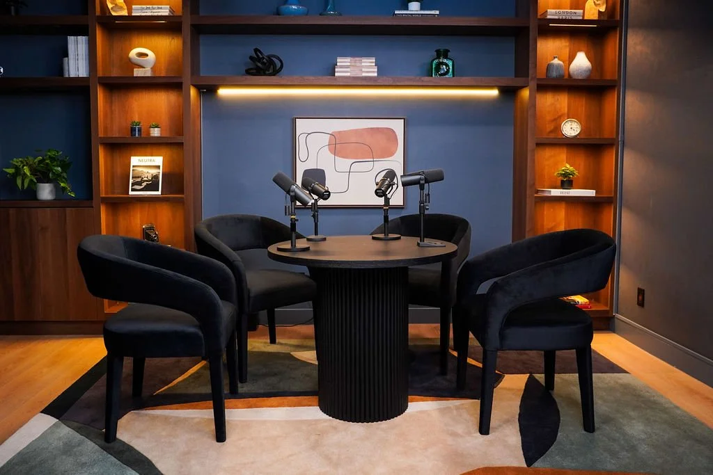 4-person setup with black lounge chairs and round table beneath abstract wall art in the Brooklyn set