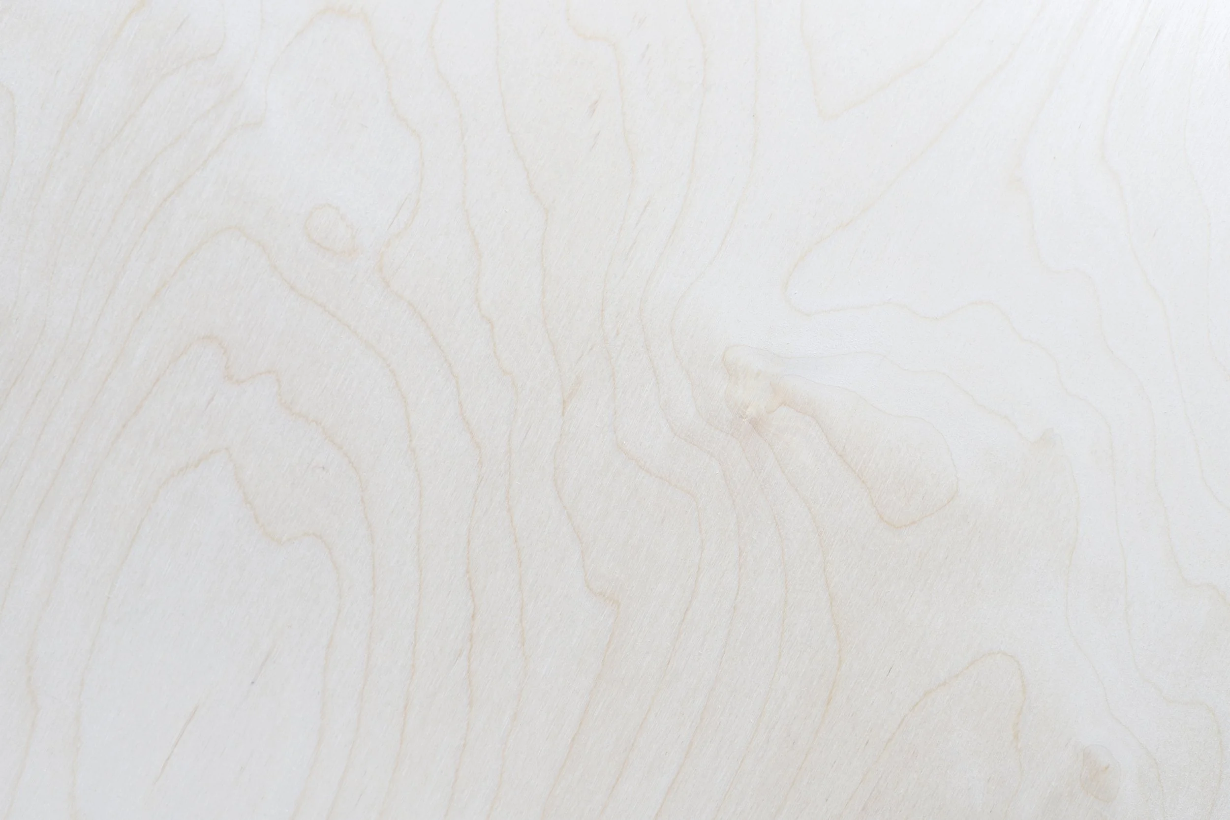 A light-colored, smooth wood surface with visible fine wood grain patterns.