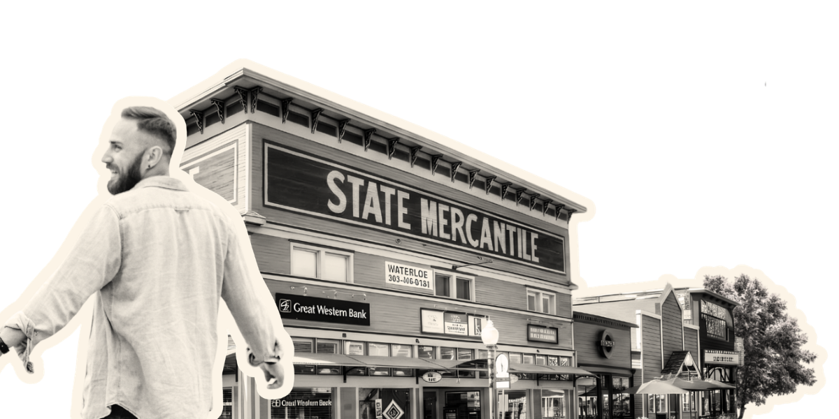 Empty outdoor café seating area on a boardwalk with tables, chairs, and umbrellas, beside shops and businesses, with an orange semi-circle in the sky.