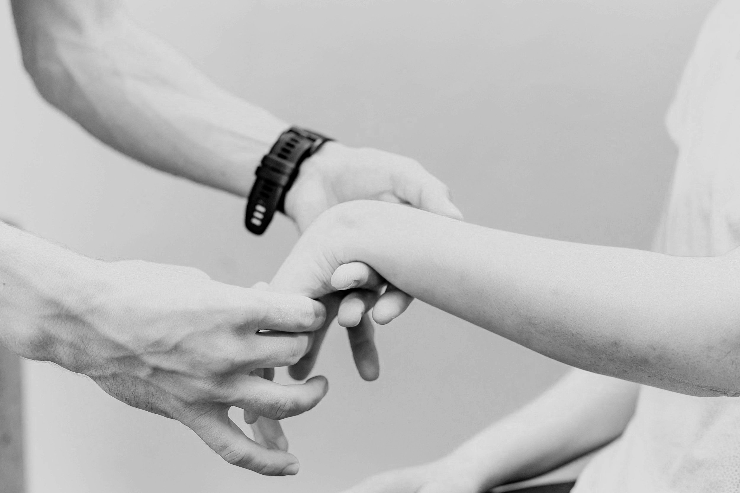 Black and white image of a person holding another person's wrist