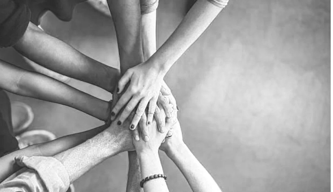 A group of diverse hands stacked together as a symbol of teamwork and unity.