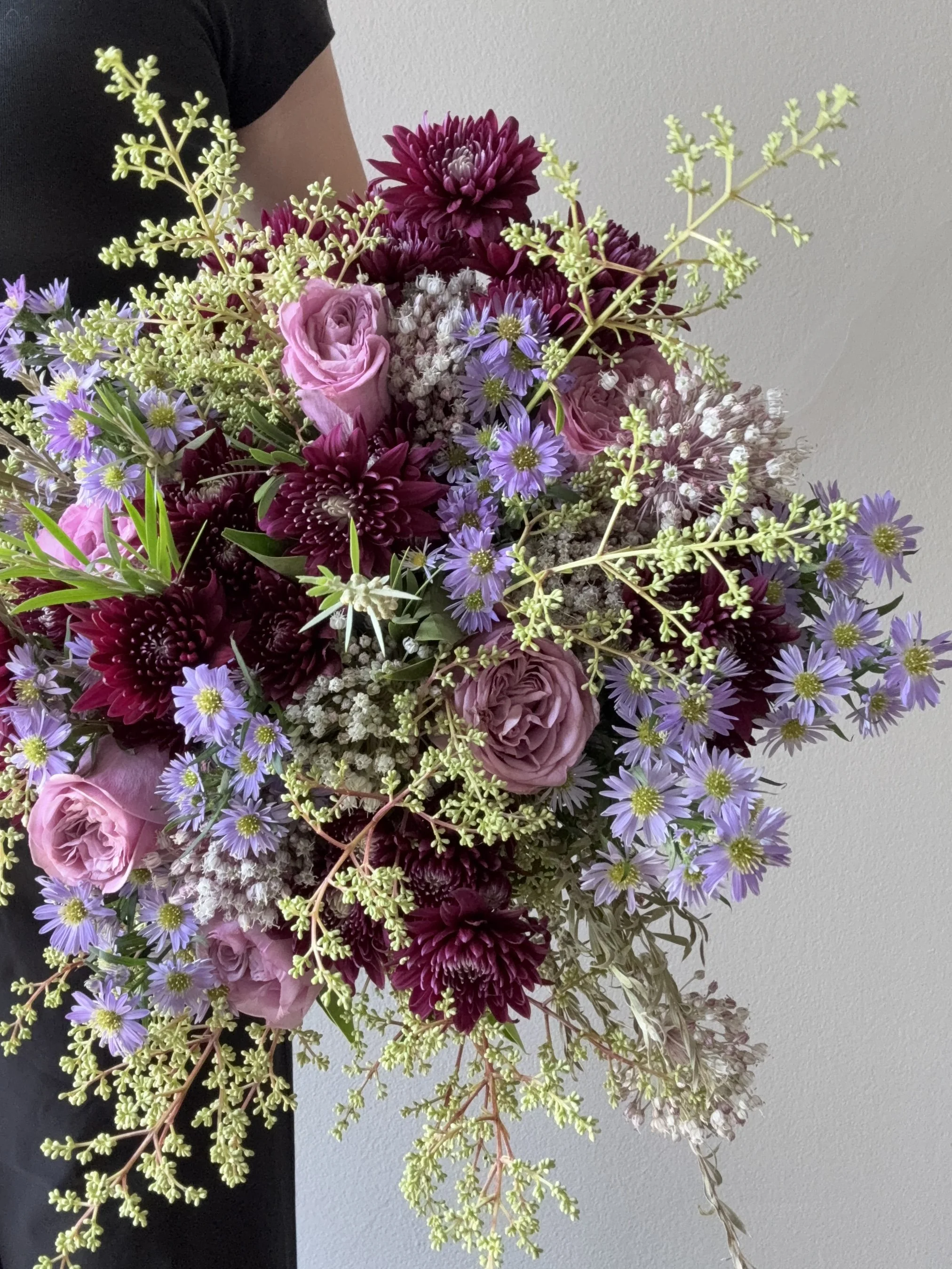Moody purple and burgundy floral arrangement in hand