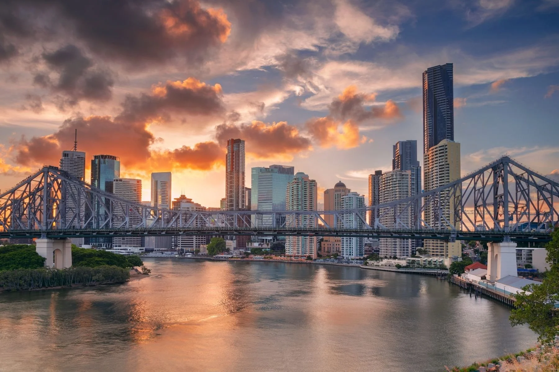 Brisbane river skyline at sunset with Story Bridge and city buildings reflected in water