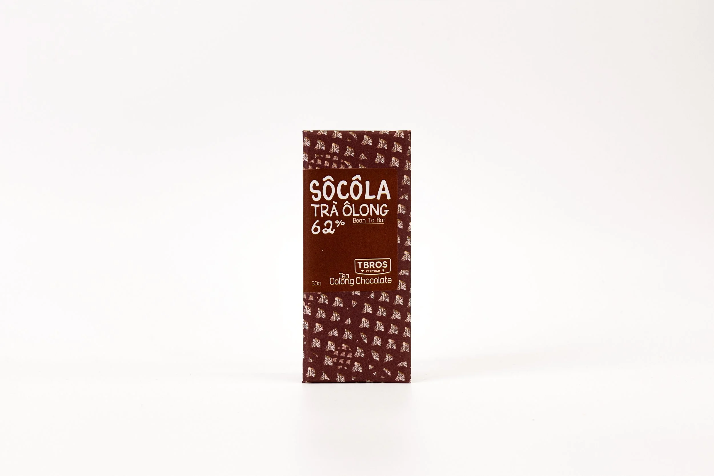 A brown package of Socola Tra Wowng 62% dark chocolate, featuring patterned design with small geometric shapes, standing upright on a plain white background.