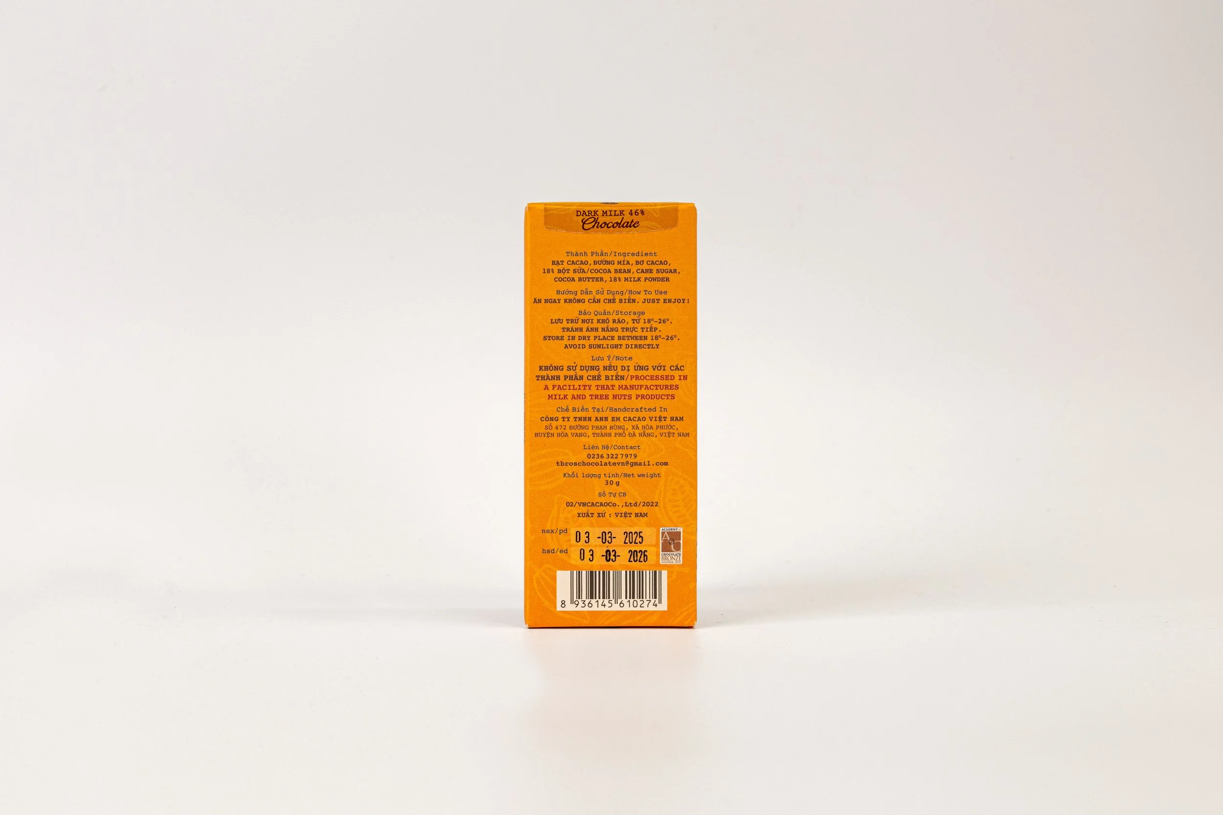 Back of a chocolate product box in orange color with text in Vietnamese and English, barcode at bottom.