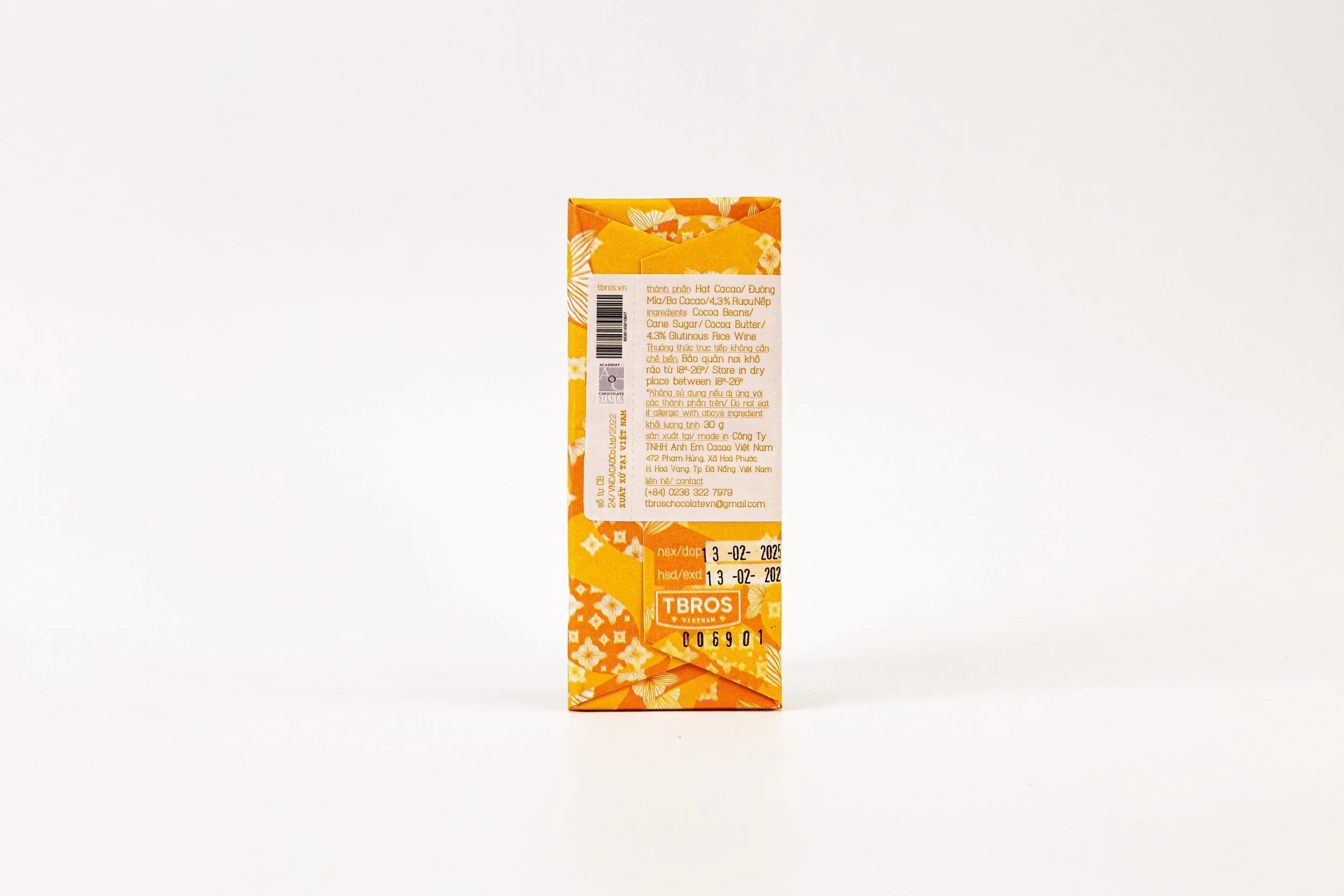 Backside of a small, rectangular box with orange and white floral pattern, featuring product information, barcode, and expiration date.