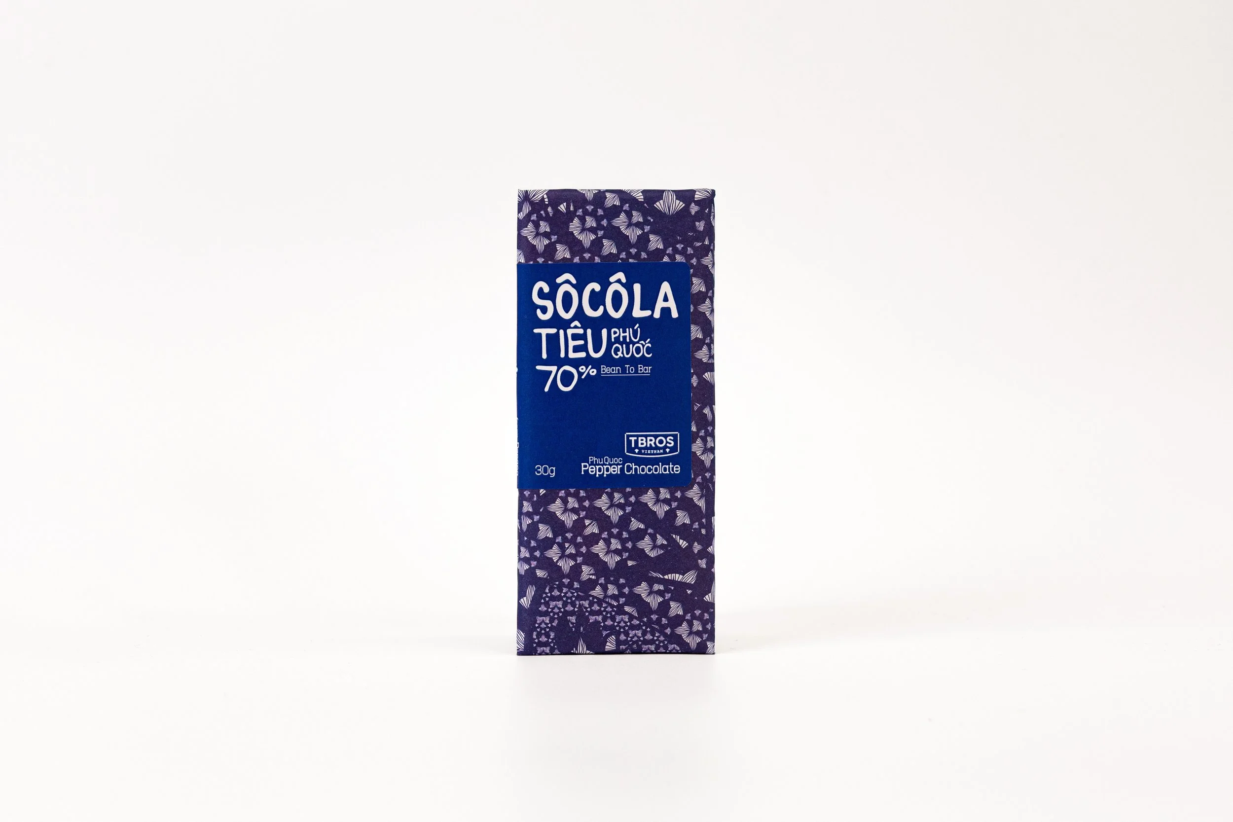 A bar of Phu Quoc pepper chocolate in purple packaging with white floral patterns and a blue label.