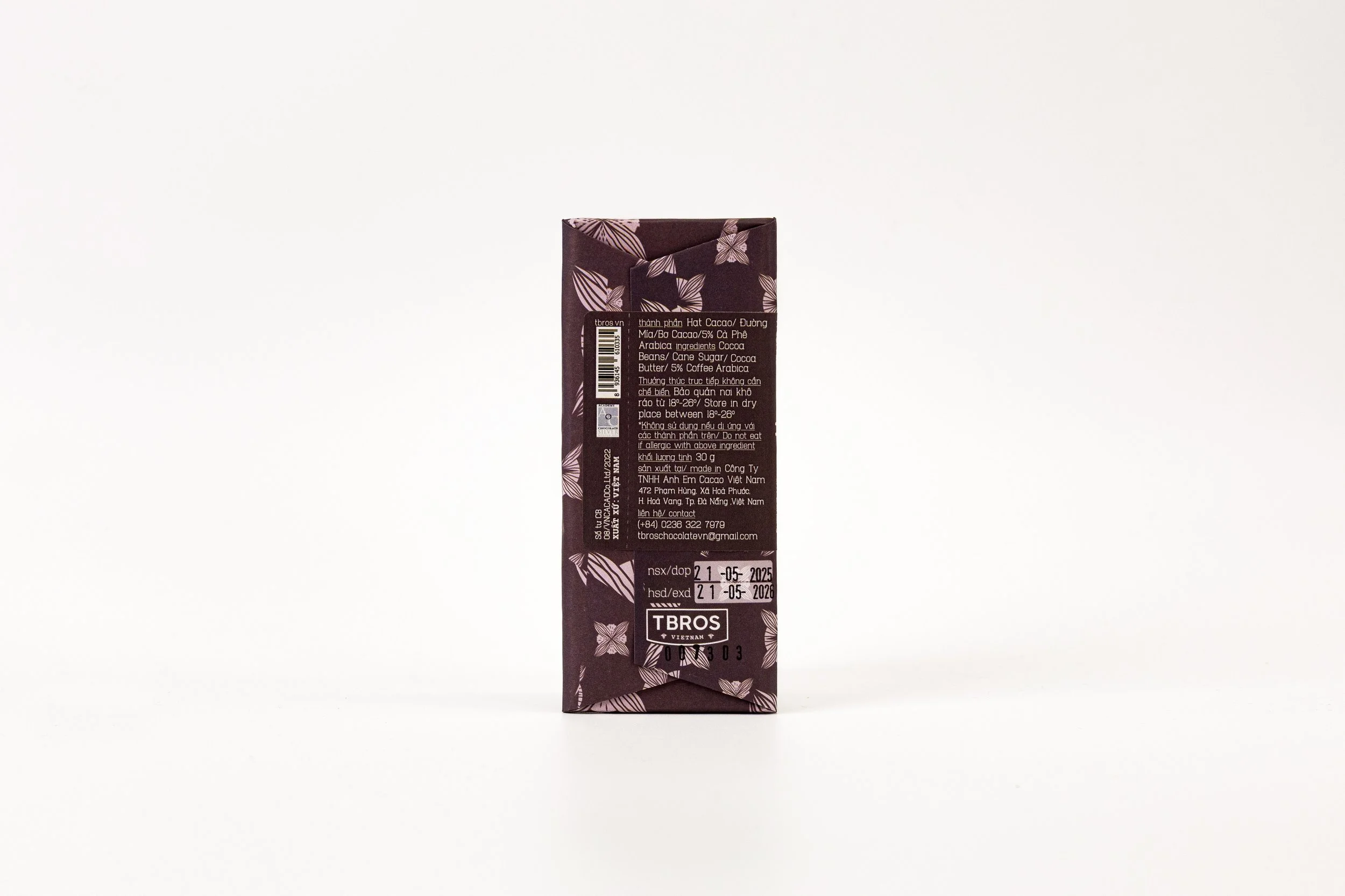 Back of a dark purple chocolate box with floral patterns and nutrition information, branding, and expiry date.