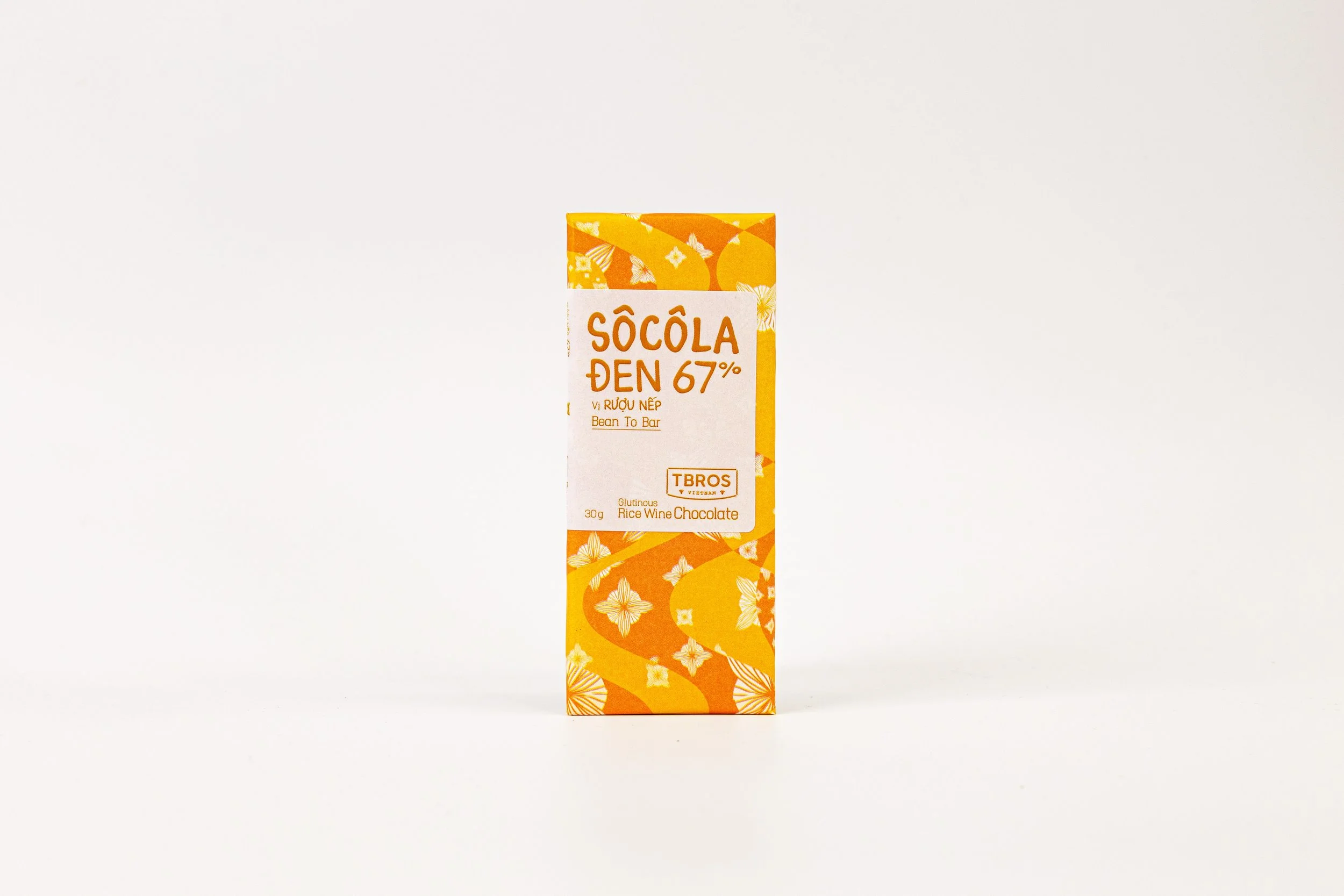 Orange and white chocolate bar with Vietnamese and English text, labeled as Sôcôla Đen 67% Bean To Bar, rice wine flavor, 30g, gluten-free.