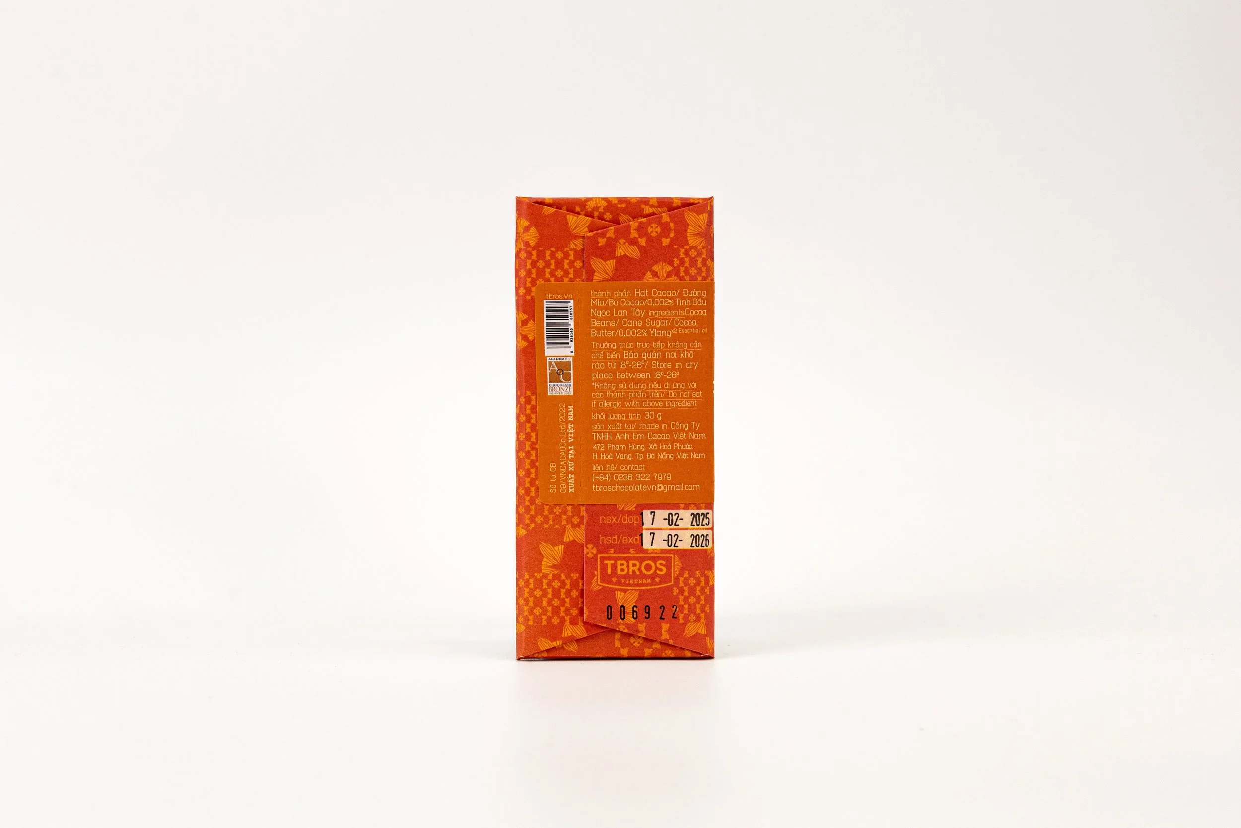 Orange chocolate bar packaging with labels and barcode, standing upright on a white background.