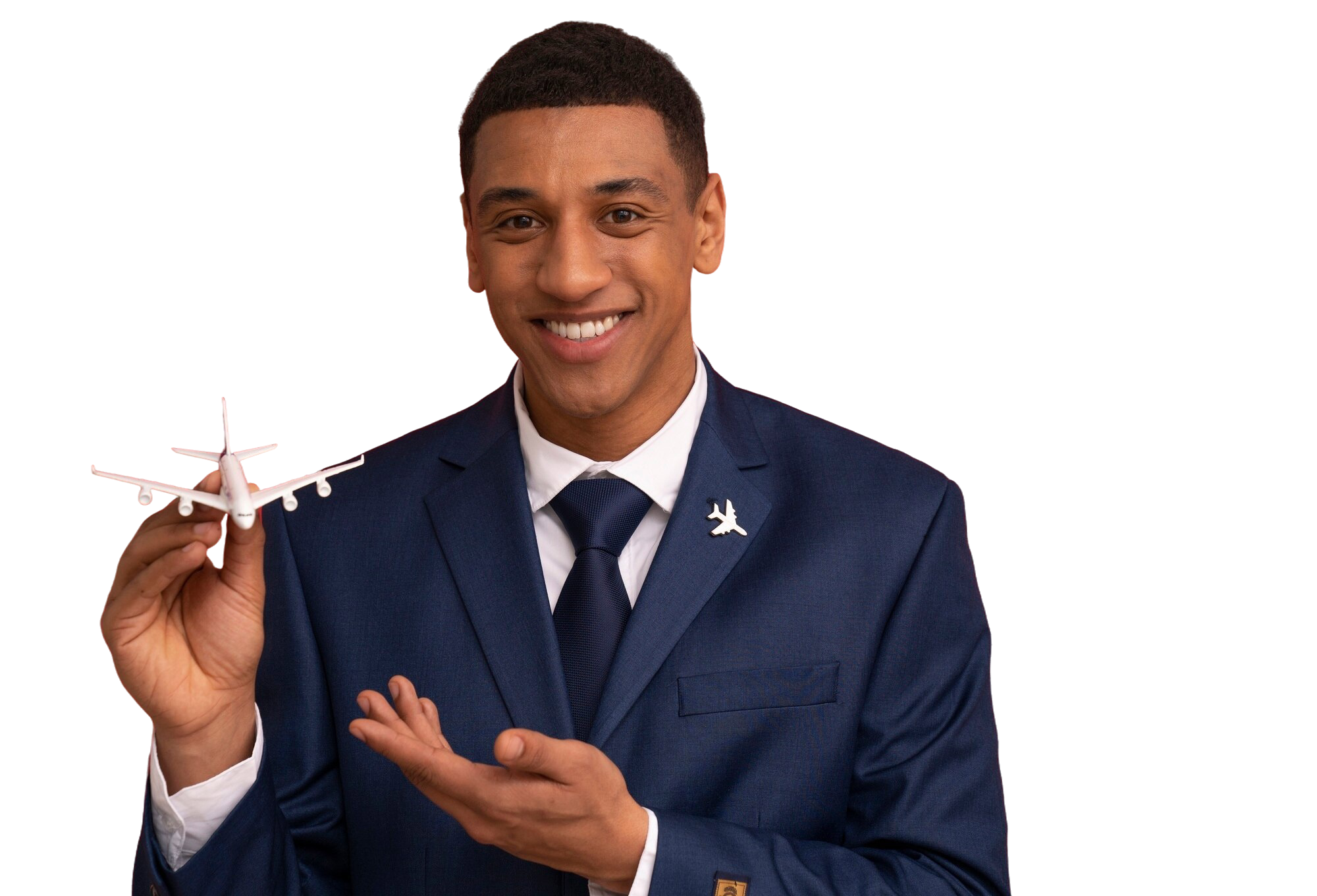 A man in a navy blue suit holding a small white airplane model, smiling, with a metal airplane pin on his lapel and a navy blue tie.